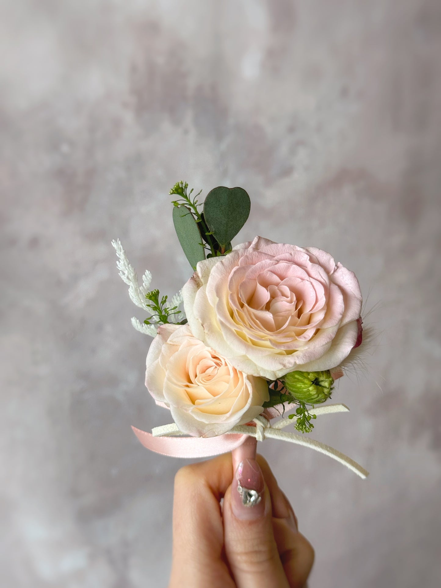 close up view of 'Adoring' fresh rose boutonniere, holding by a hand