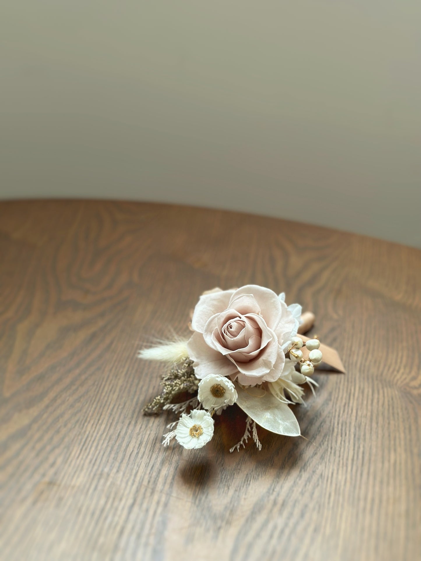 Corsage with khaki and nude brown preserved roses elegantly placed on a table, showcasing its soft neutral tones