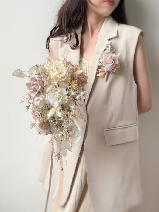 A graceful teardrop bridal bouquet in ivory, nude, and cream tones, held elegantly in front of the bride.
新娘双手捧着优雅的水滴形手捧花,象牙色、裸色和奶油色交织出柔和浪漫的气息。