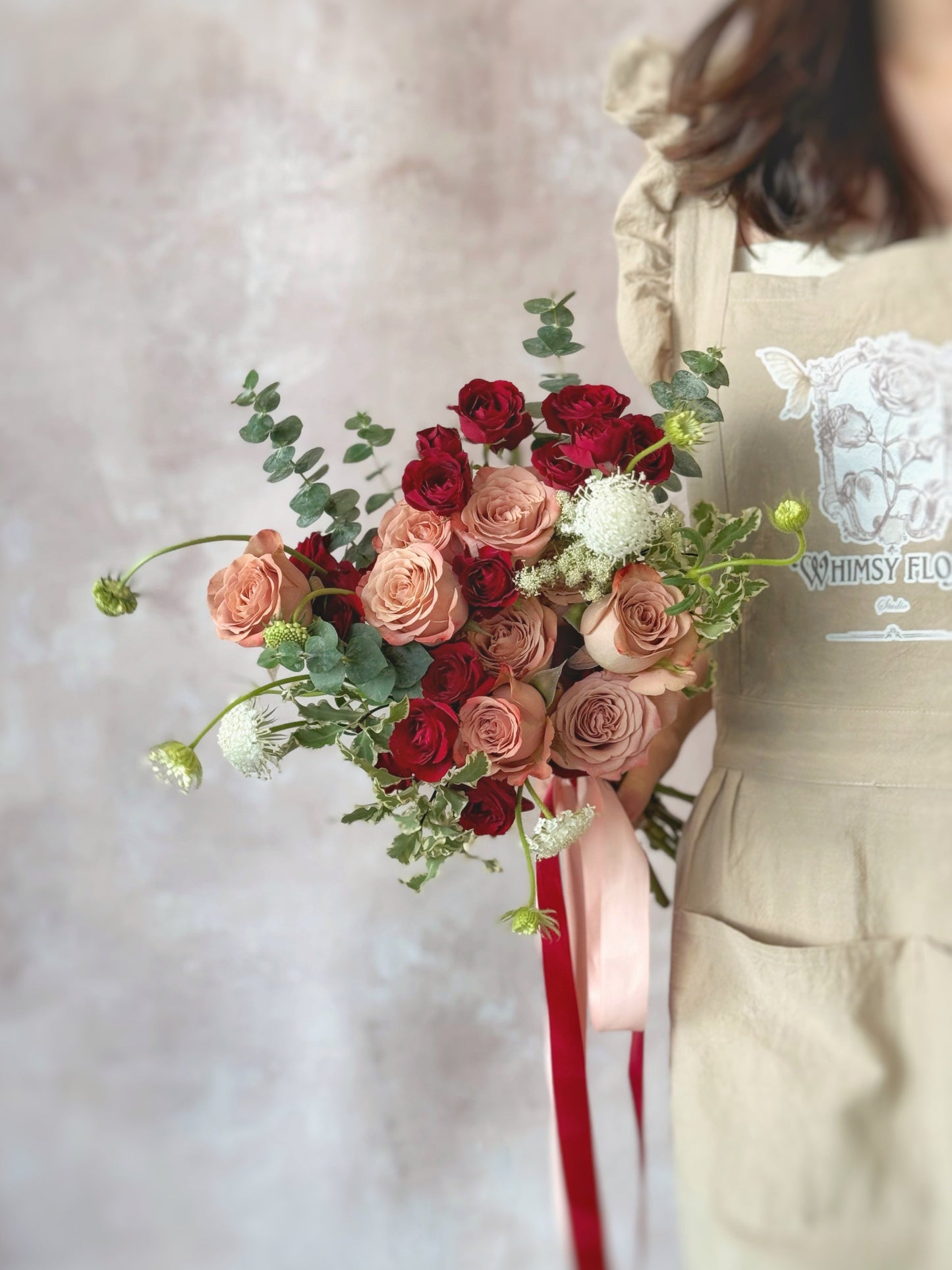 Amelia fresh flowers fan shaped bridal bouquet grand size front view, a stunning bridal bouquet featuring red, maroon, and nude pink blooms, accented with red spray roses and cappuccino roses.