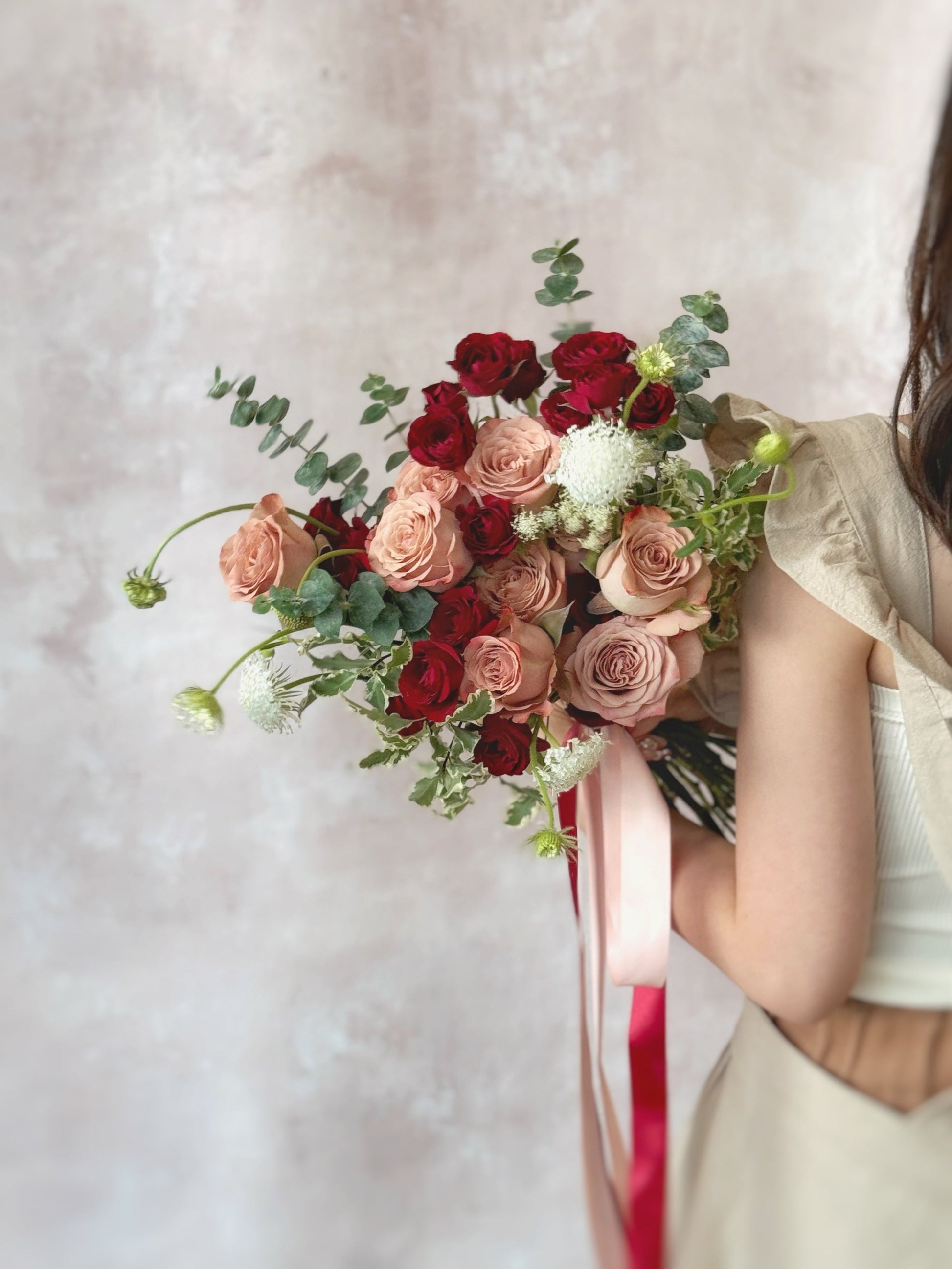 Elegant bouquet with a rich blend of red, maroon, and nude pink flowers, highlighted by delicate red spray roses and cappuccino roses.
