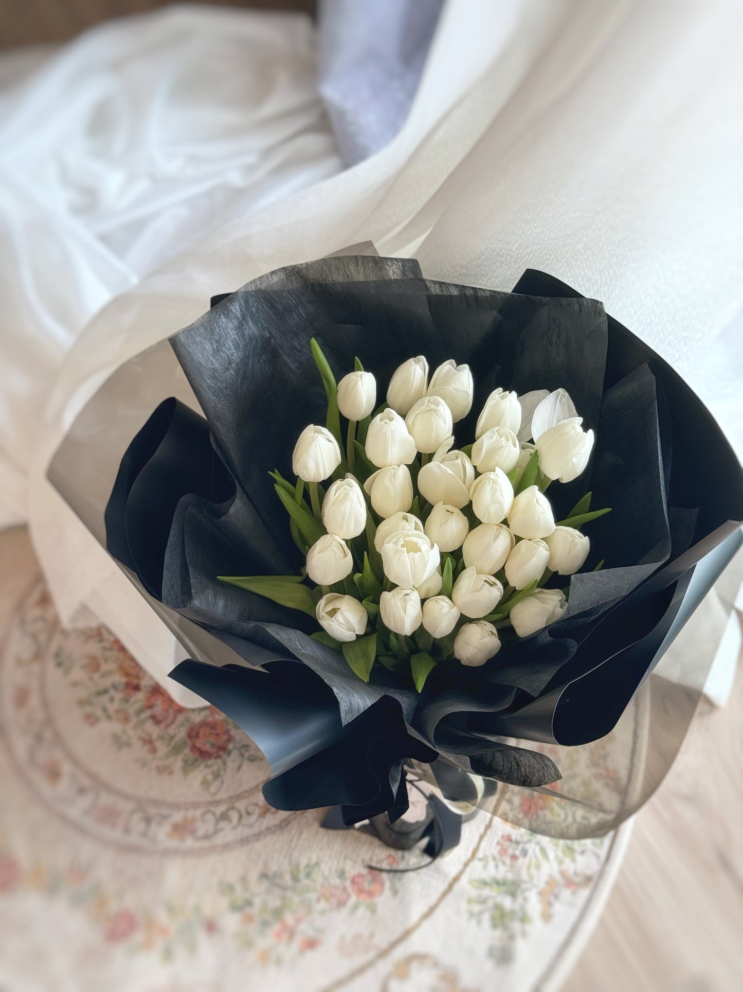 30 stalks of white tulips bouquet on a vintage carpet top view