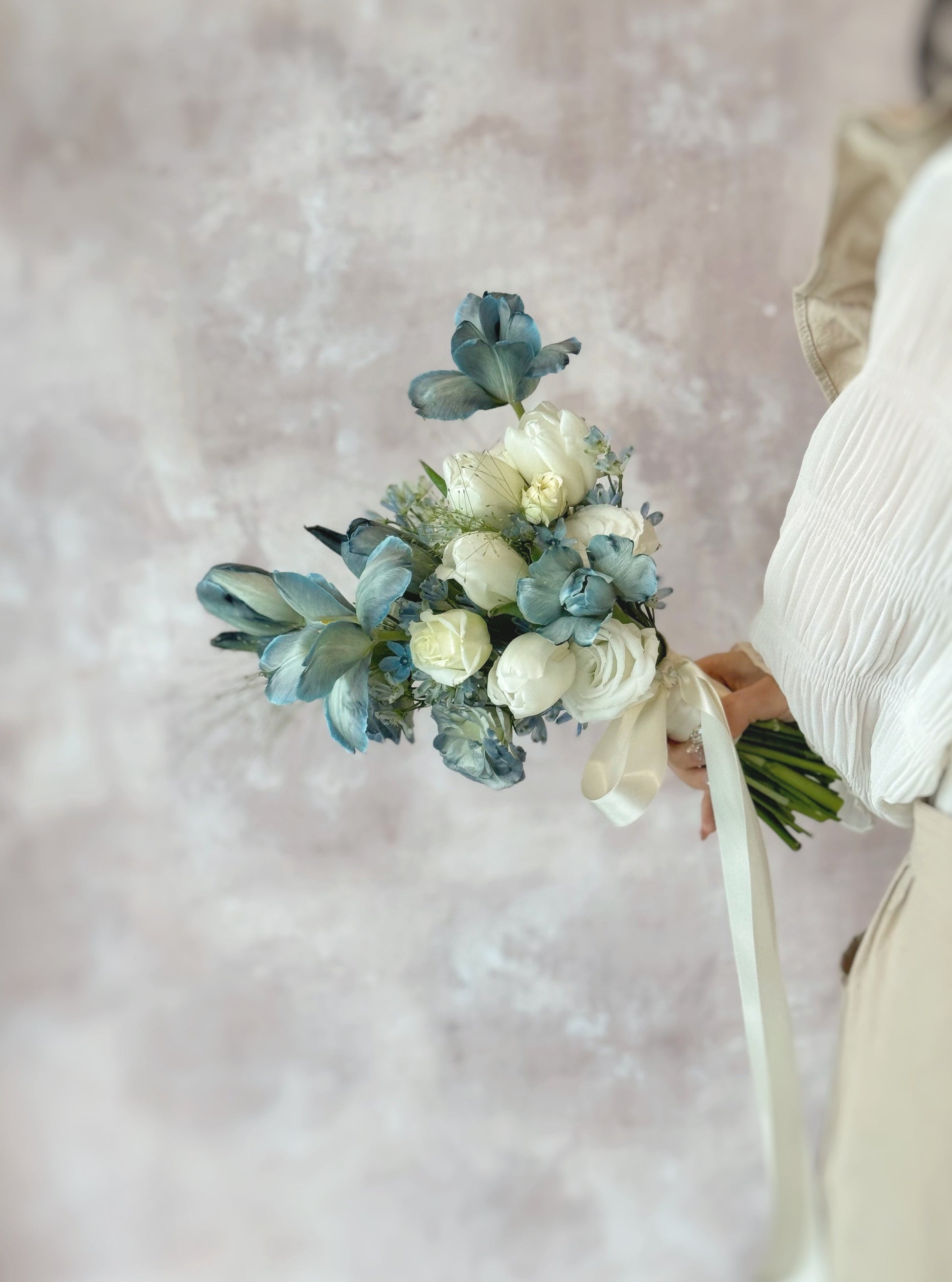 A bride holding a fairy-tale-inspired dusty blue bouquet, perfect for a whimsical wedding theme
新娘手持仙境般的灰蓝色捧花,适合梦幻婚礼主题