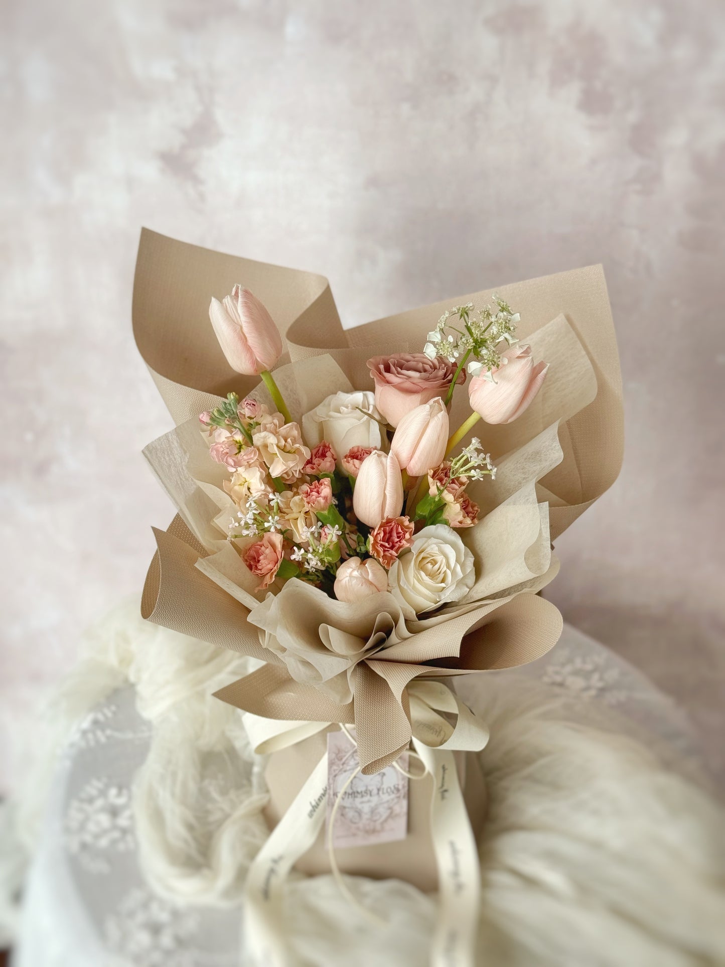 Blushie Tulip bouquet resting on a table, showcasing the soft pink tulips arranged simply to enhance their natural beauty. 花束放置在桌上,柔和粉色郁金香自然排列,呈现温柔浪漫的氛围。