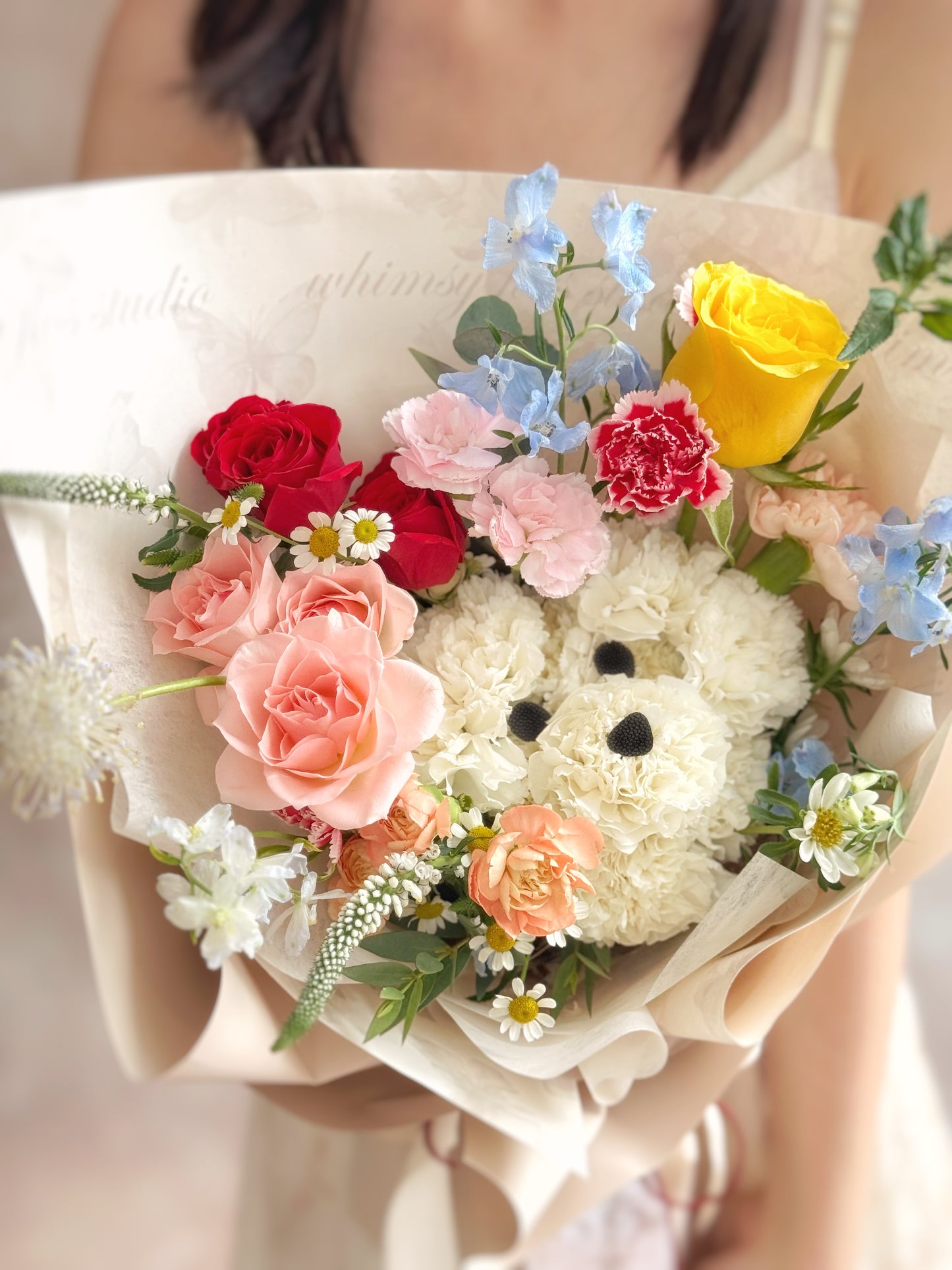: Close-up of the puppy face crafted from white carnations, with details like eyes and nose delicately added — a fun and lovable touch.
特写镜头聚焦康乃馨打造的小狗脸部,眼睛与鼻子细节精致可爱,是不可抗拒的温暖设计。