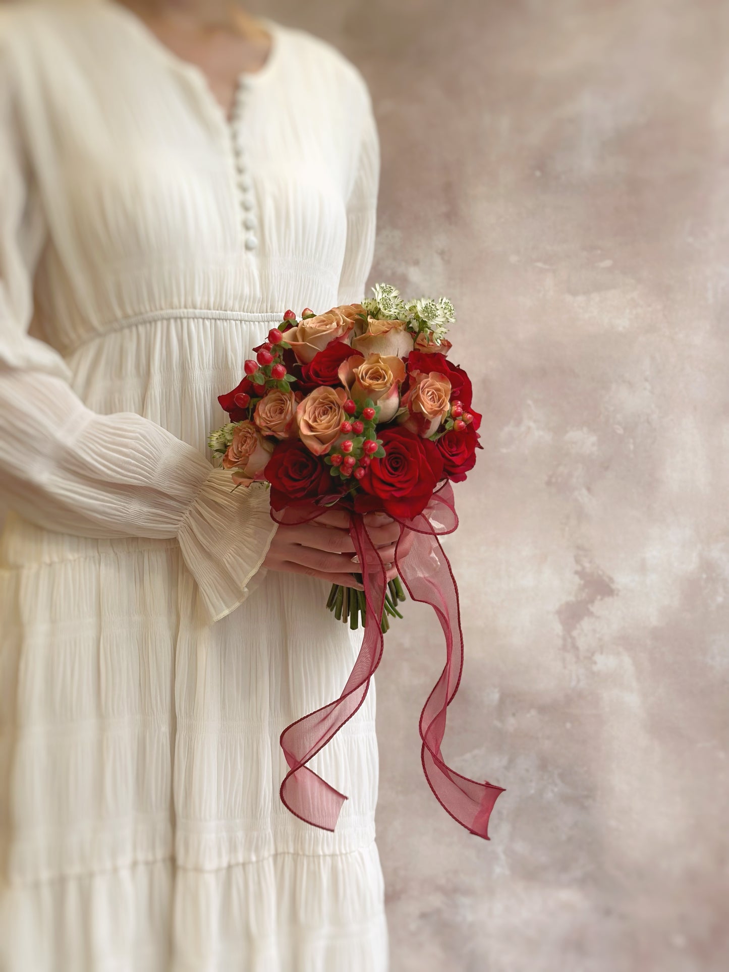 The bouquet held in front of a bride’s gown, enhancing the classic and sophisticated wedding look.
新娘手持捧花,搭配刺绣中式婚服,展现经典高雅的婚礼造型。