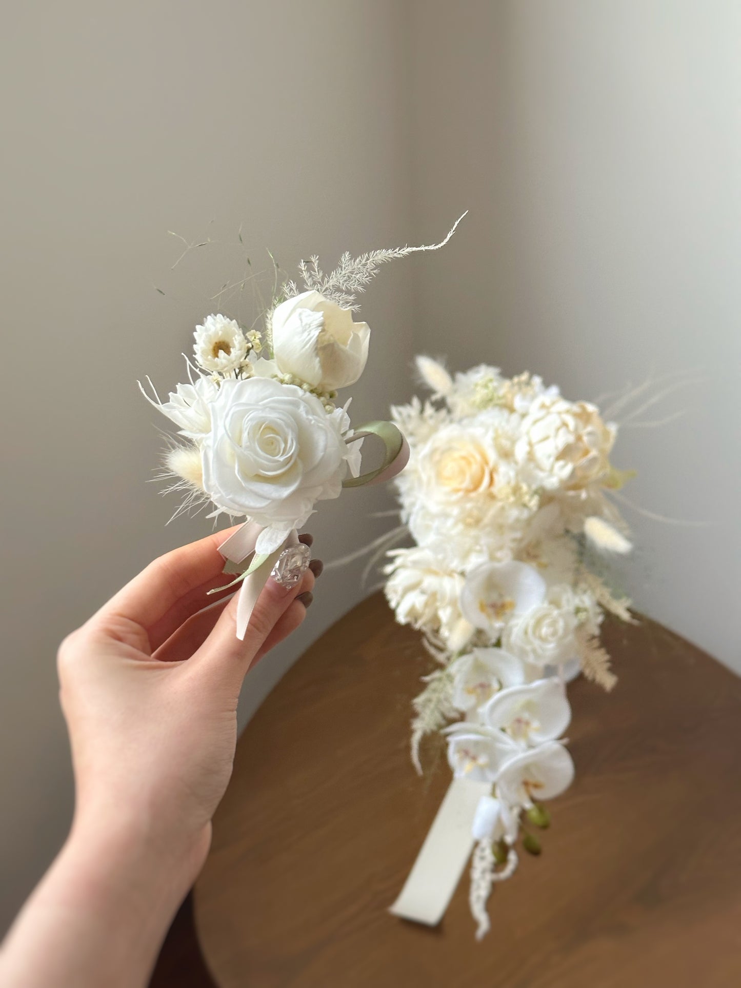 Elegant white boutonniere displayed alongside a matching teardrop bridal bouquet, perfect for a cohesive and timeless wedding look