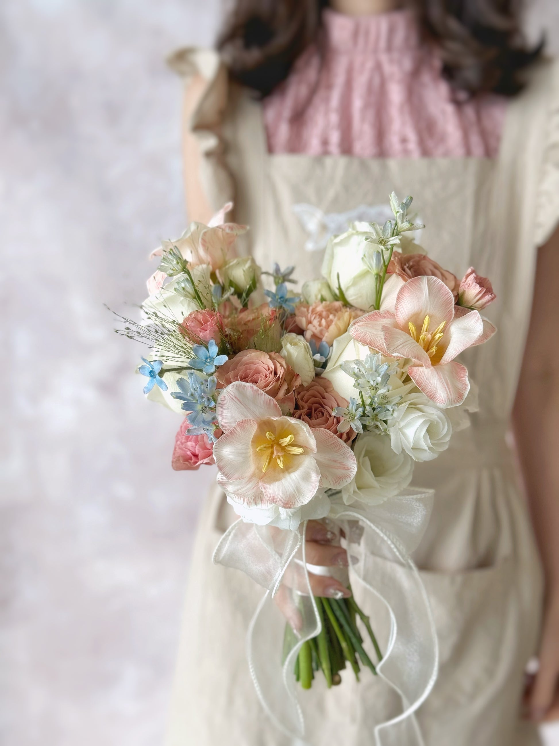 A model holding a pastel floral bouquet inspired by Rococo paintings, exuding elegance and femininity
新娘手持洛可可风格的马卡龙色捧花,散发优雅与柔美气息