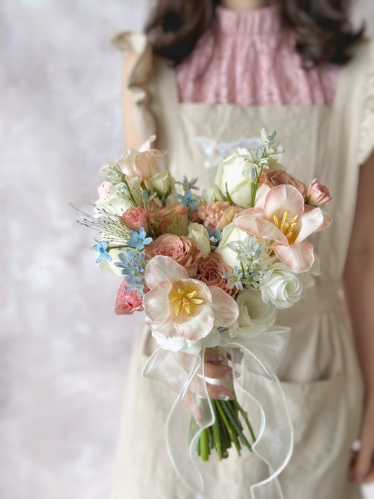 A model holding a pastel floral bouquet inspired by Rococo paintings, exuding elegance and femininity
新娘手持洛可可风格的马卡龙色捧花,散发优雅与柔美气息