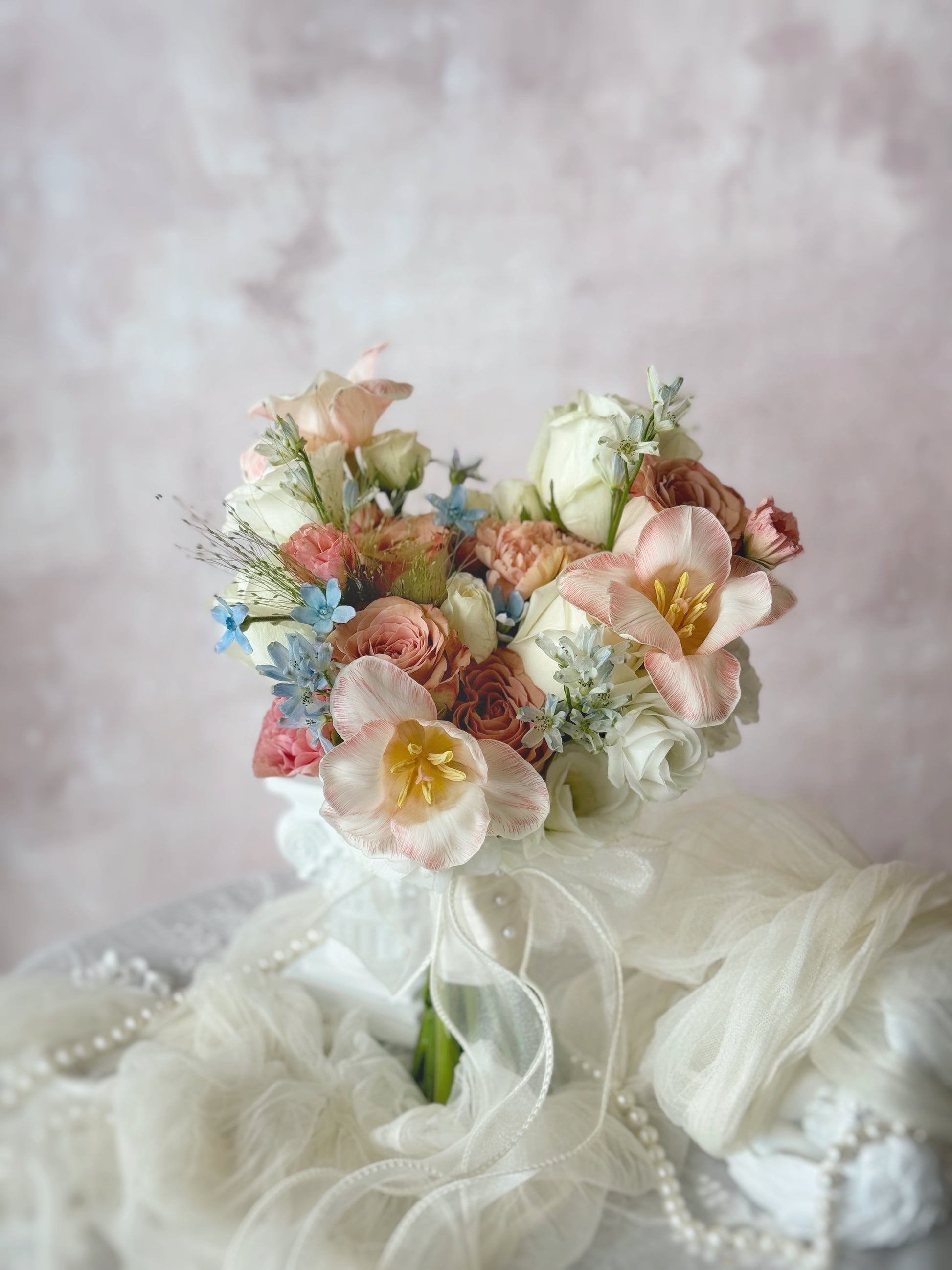 A Rococo-inspired bridal bouquet featuring pastel pink, peach, and blue flowers, radiating soft elegance and whimsy
受洛可可风格启发的婚礼捧花,融合粉色、蜜桃色和蓝色花卉,散发柔美浪漫气息