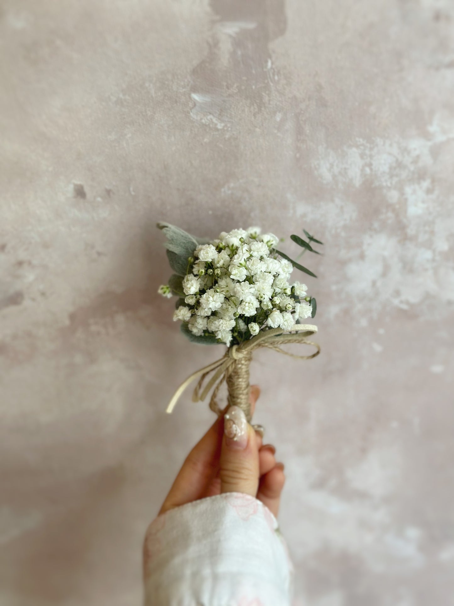 Close up view of Dainty white fresh baby breath corsage holding by a model, showing details of the design