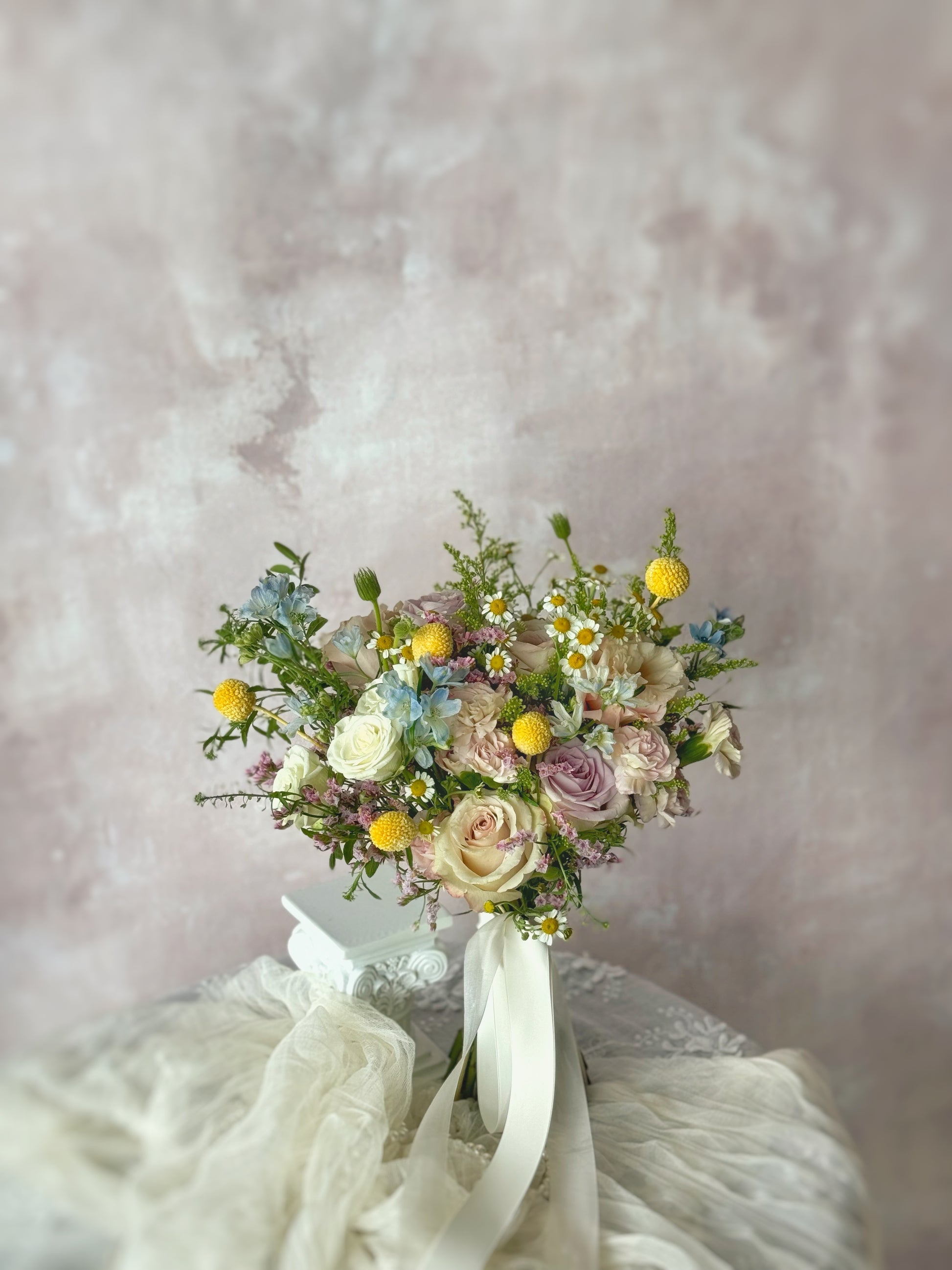DOrothea fresh flowers bridal bouquet, a whimsical pastel rose bouquet standing on a table, showcasing soft hues of lilac, green, yellow, blue, and pink