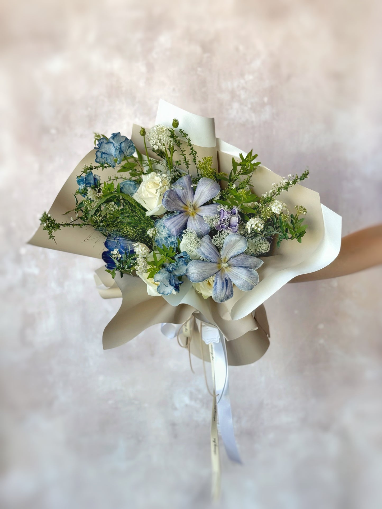 Bouquet held at arm’s length, with only hands and extended arms visible, drawing focus to the dyed tulips and moody palette.
花束由手臂延伸持握,仅展示花面,突出染色郁金香与深色调搭配的视觉焦点。