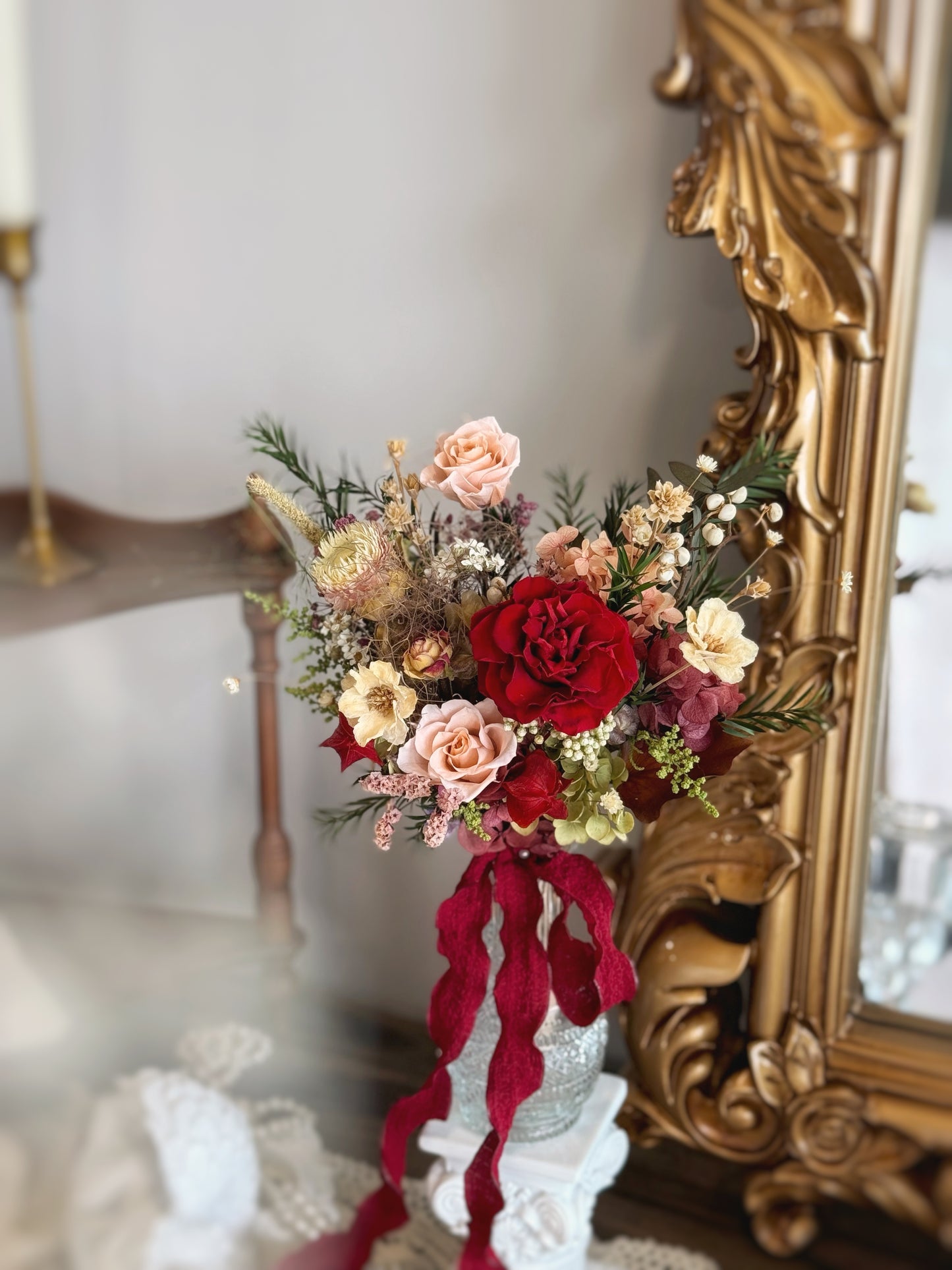 Faerie flame preserved flowers bridal bouquet front view in a vase. A striking preserved flower fan-shaped bouquet displayed elegantly on a table, featuring deep maroon, vintage red, and soft nude, peach, and yellow hues.
一款精美的扇形永生花捧花,深酒红、复古红、裸色、蜜桃黄等色彩交融,在桌面上优雅呈现。