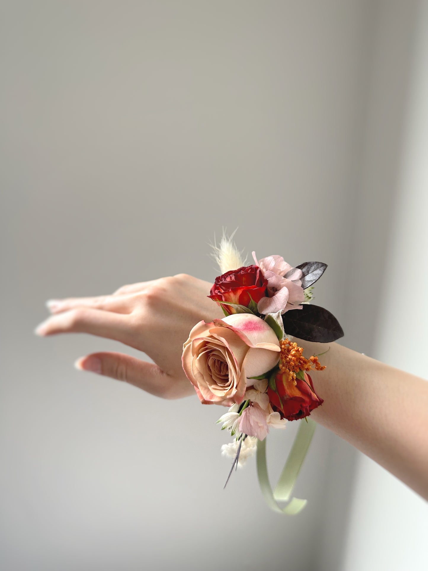 Close up view of faye fresh cappuccino rose wrist corsage, worn by model's wrist.
