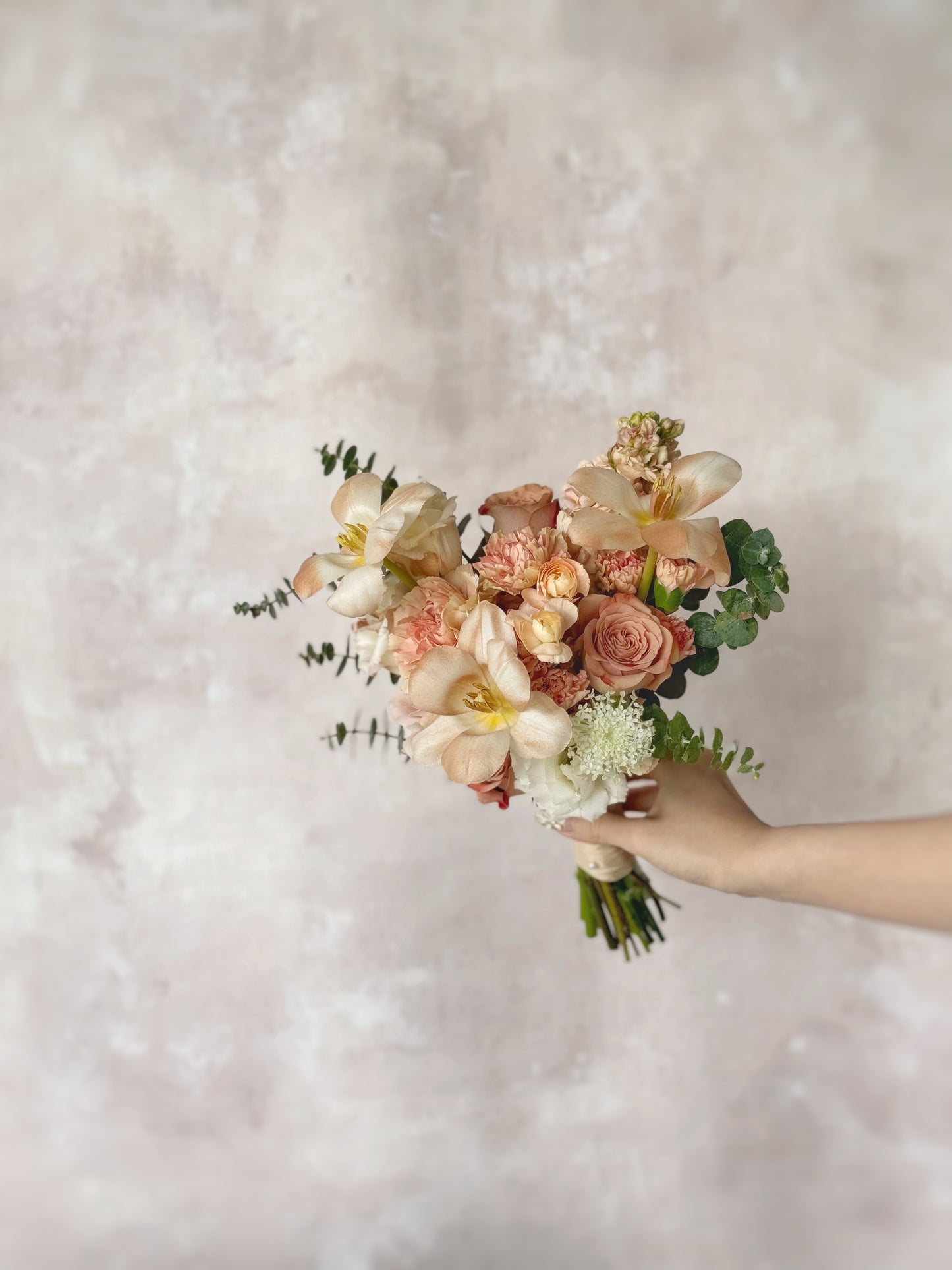 A romantic blend of cappuccino roses and light brown tulips, delicately arranged with pastel flowers and olive green accents
柔和复古色调的新娘捧花,与新娘优雅造型完美相配;卡布奇诺玫瑰与粉彩花朵的层次感和质感,塑造迷人而经典的新娘捧花