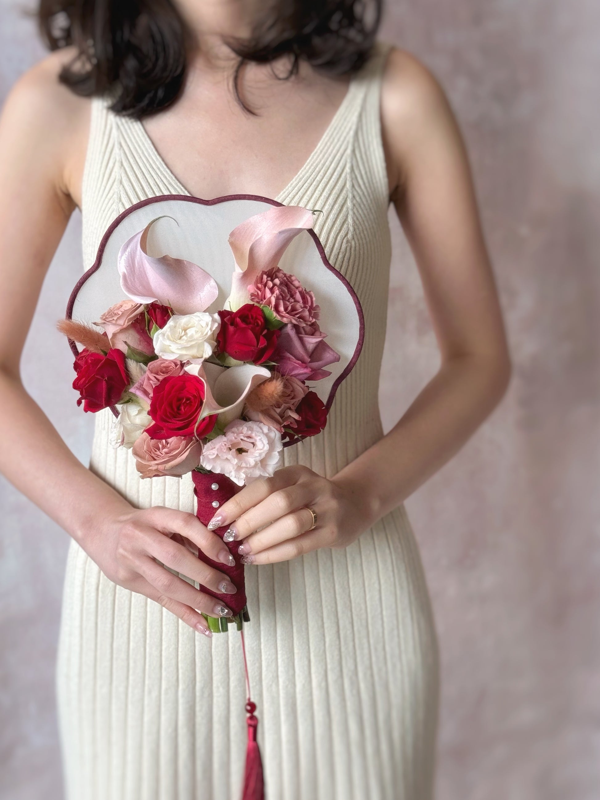 A unique floral bridal fan, beautifully hand-tied with fresh flowers, held by a bride in a traditional Chinese wedding look. 时尚现代的东方风格新娘扇花束,鲜花精美排列在传统中式婚礼扇上