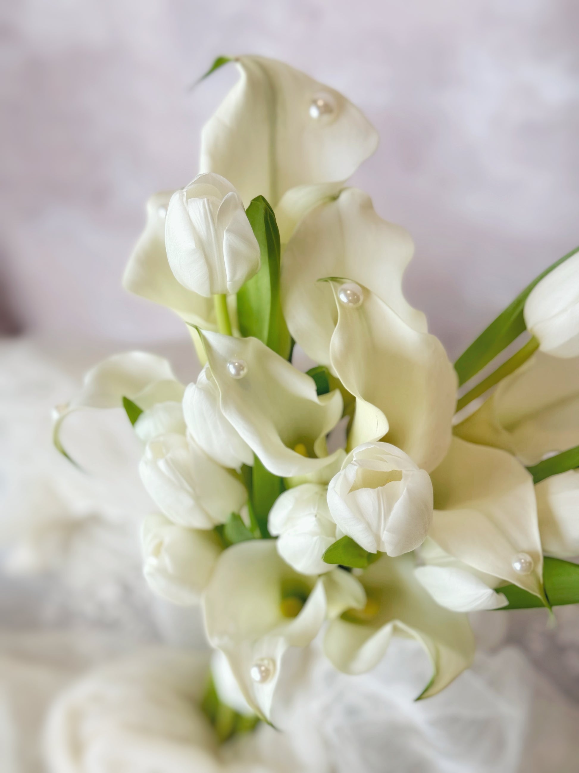 Genuine fresh flowers bridal bouquet, close-up of a calla lily and tulip bridal bouquet, highlighting the smooth petals and graceful curves of each bloom with pearls
极简新娘捧花特写,柔和的白色郁金香与流畅的马蹄莲展现精致之美