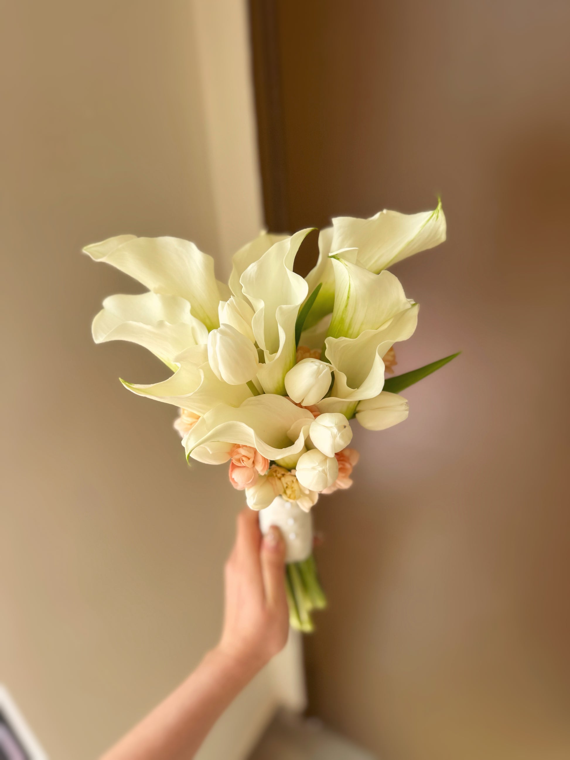 Bridal bouquet held elegantly by model, showcasing the bouquet’s modern simplicity and soft, warm colors in a real-life moment.
手持新娘花束,展示花束现代简约风格及柔和暖色调的真实生活场景。