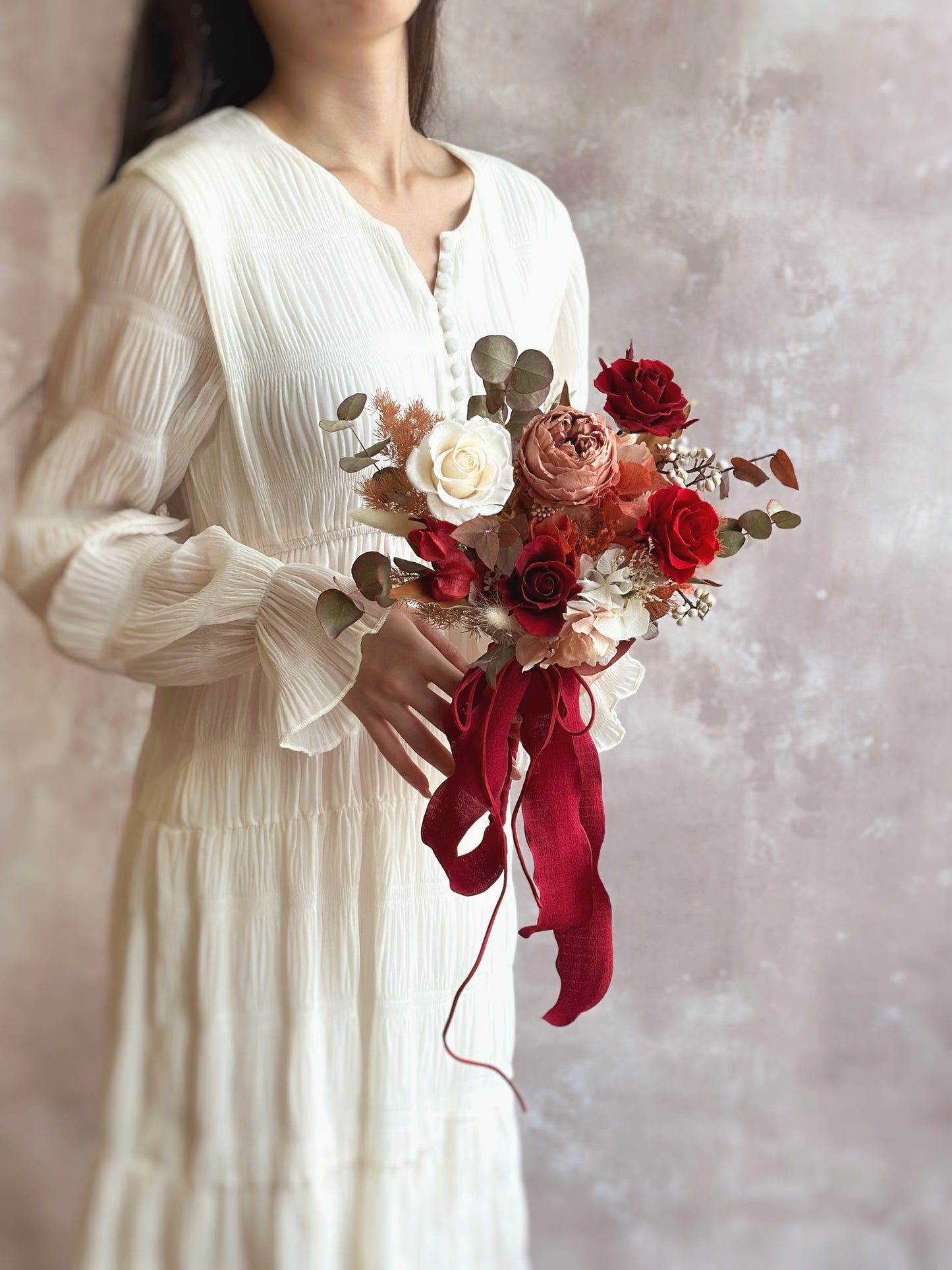 Holding a autumnal theme preserved flowers bridal bouquet