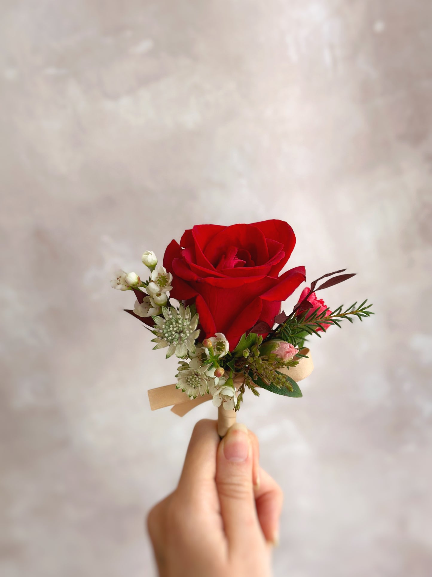 Red rose boutonnière with lush greeneries
