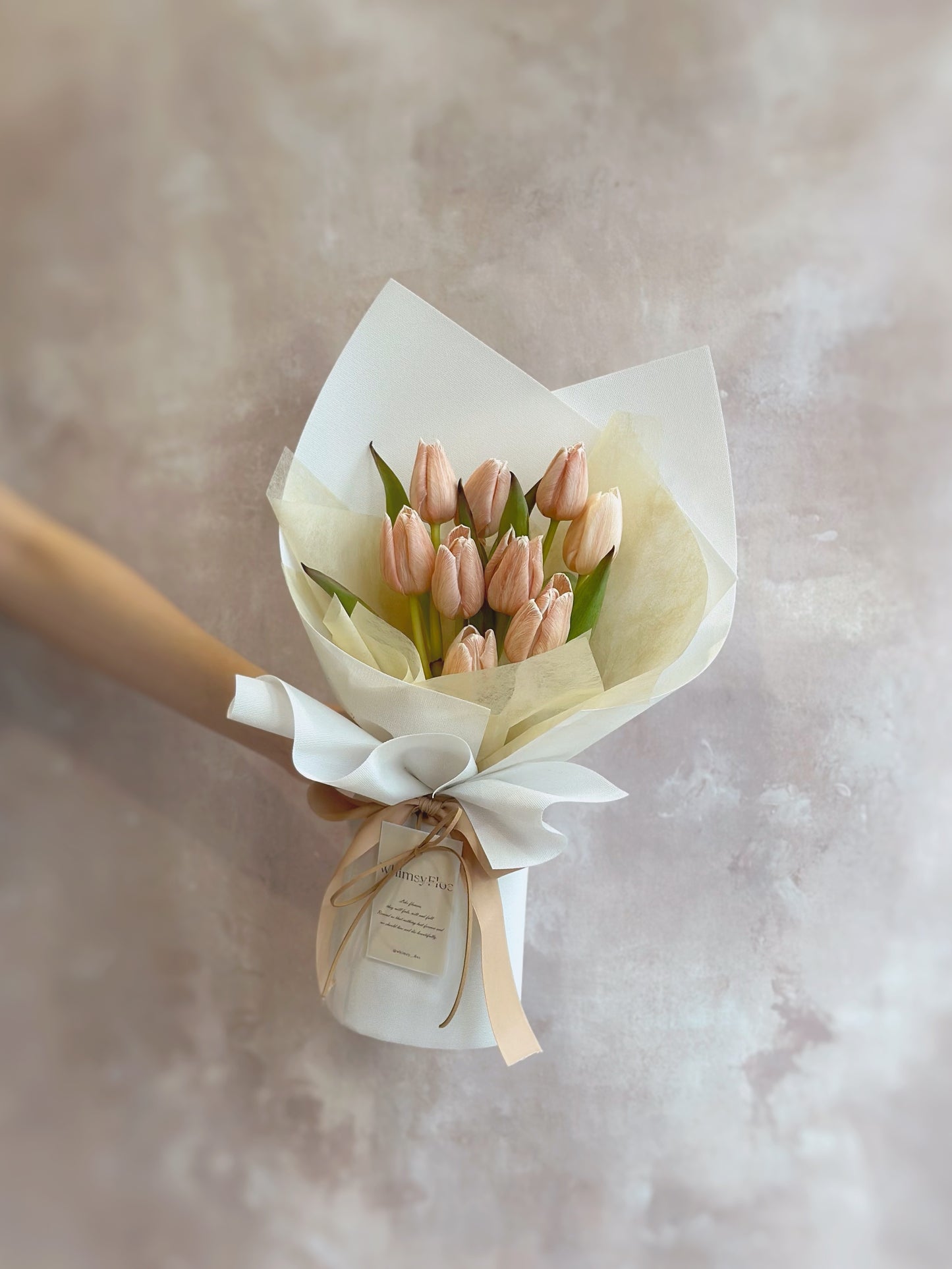 Holding a lighter tone brownie stem dyed tulips bouquet