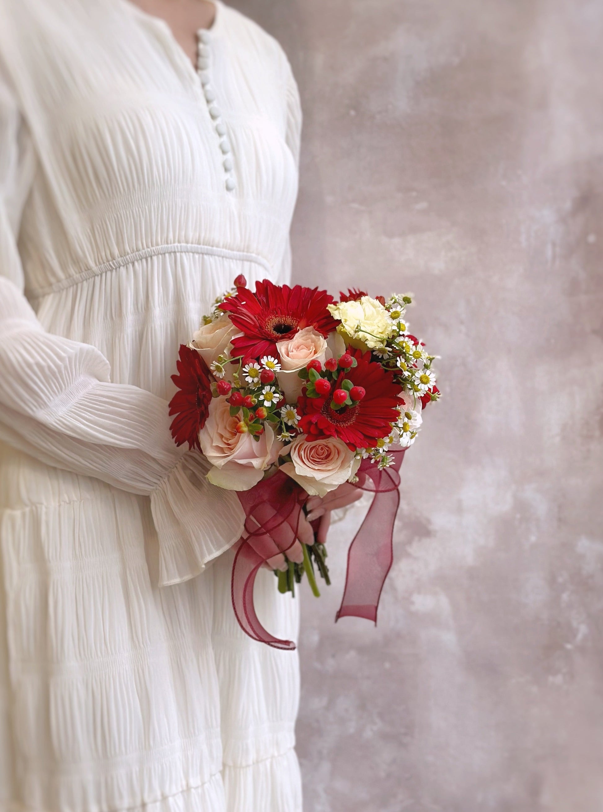 Model holding a round bouquet featuring gerbera, roses, and chamomile
新娘手持圆形捧花,融合洋甘菊、玫瑰与雏菊的清新搭配