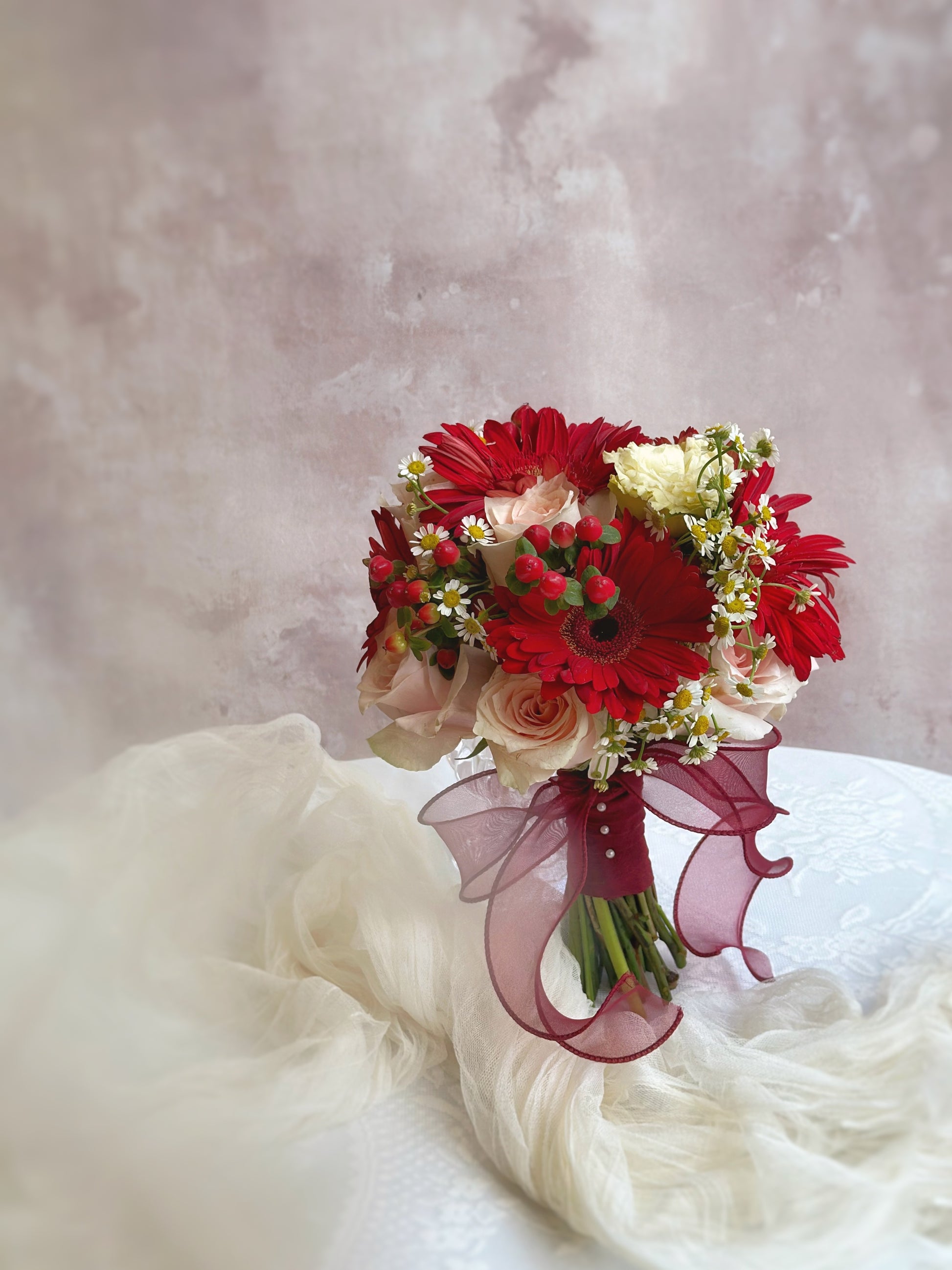 Bright red berries, gerbera and peachy rose add a pop of color to this charming bridal bouquet
鲜艳的红浆果为这款迷人的新娘捧花增添活力