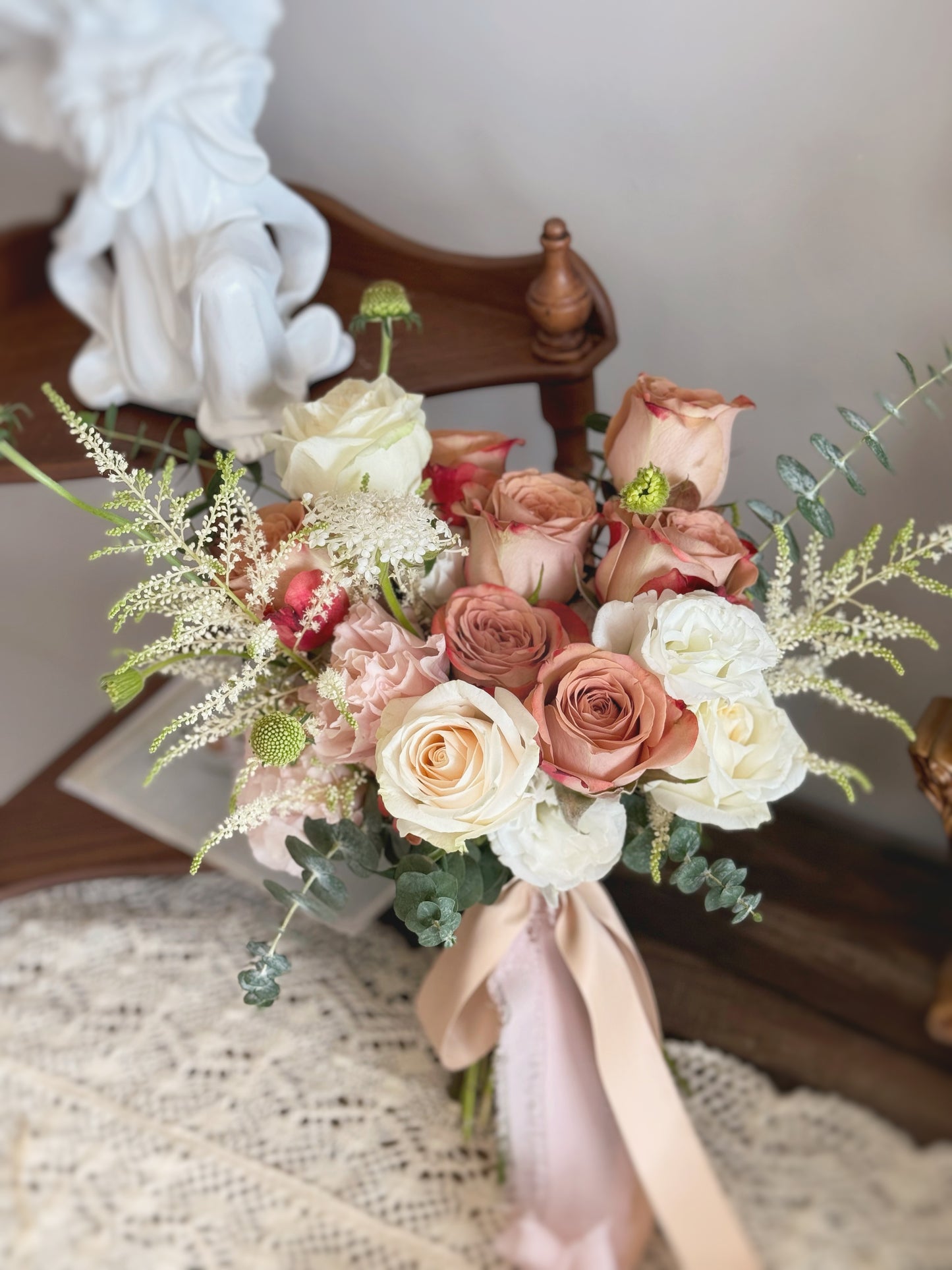 Front view of a free-flowing fan-shaped bridal bouquet featuring cappuccino roses, astilbe, and lush greenery for an elegant yet relaxed garden look