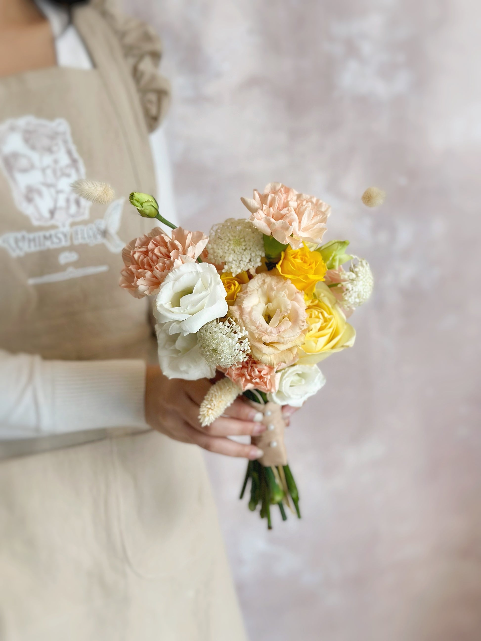 Soft peach and sunny yellow florals come together in a radiant bridal bouquet
柔和蜜桃粉与阳光黄色花朵交织,打造明亮婚礼造型