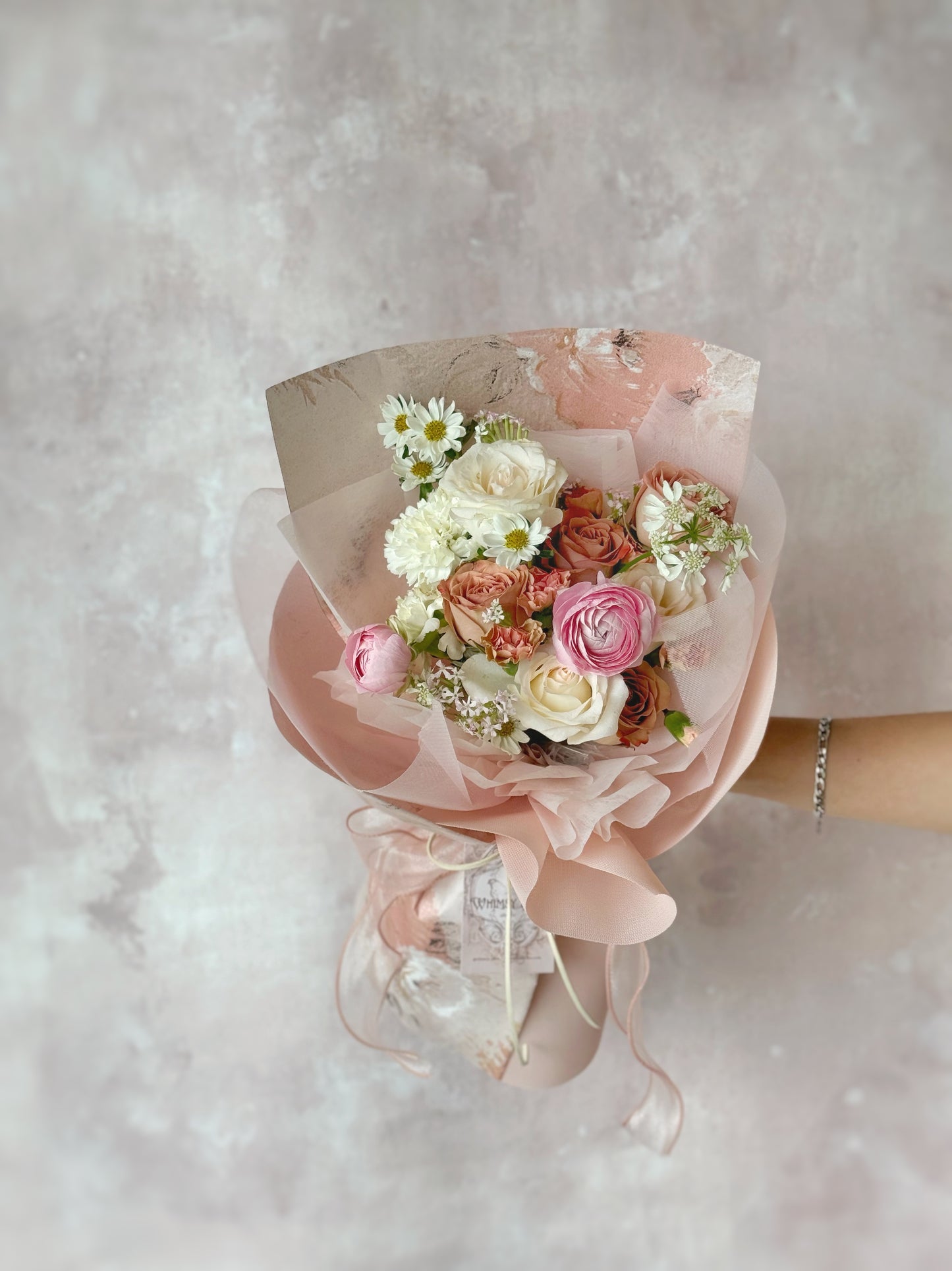 Close-up of delicate luxe size bouquet, blush-toned petals and sheer ribbon, highlighting the subtle romantic touches.
中: 特写镜头呈现柔粉花瓣与薄纱蝴蝶结,细节尽显浪漫气息。