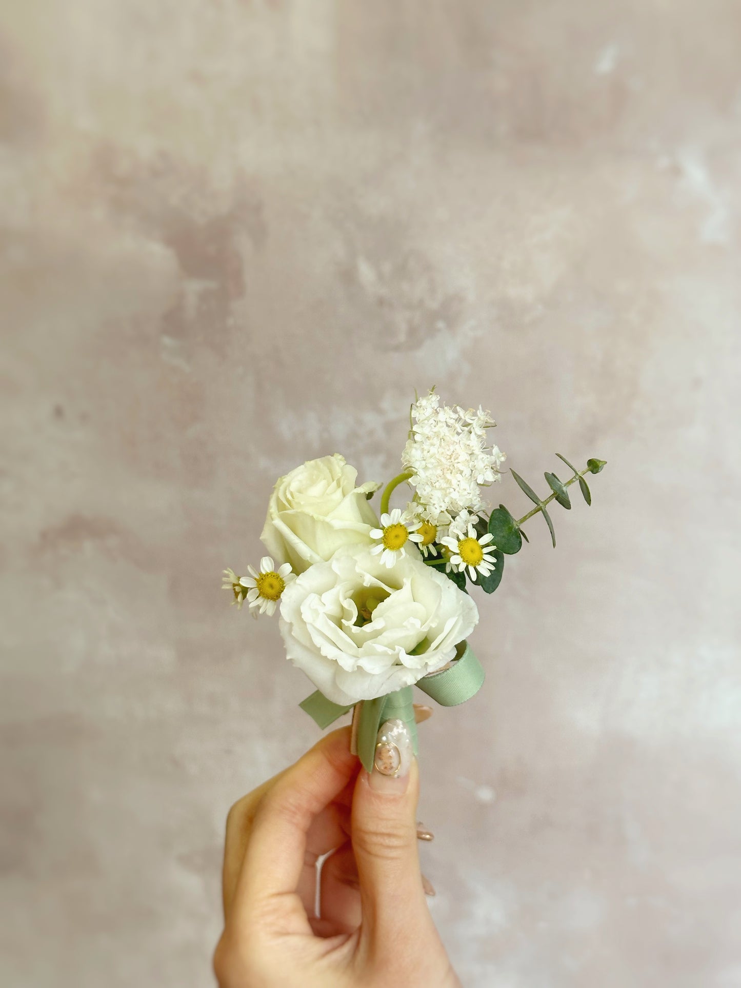 holding 'Lace' fresh flowers boutonniere, front view