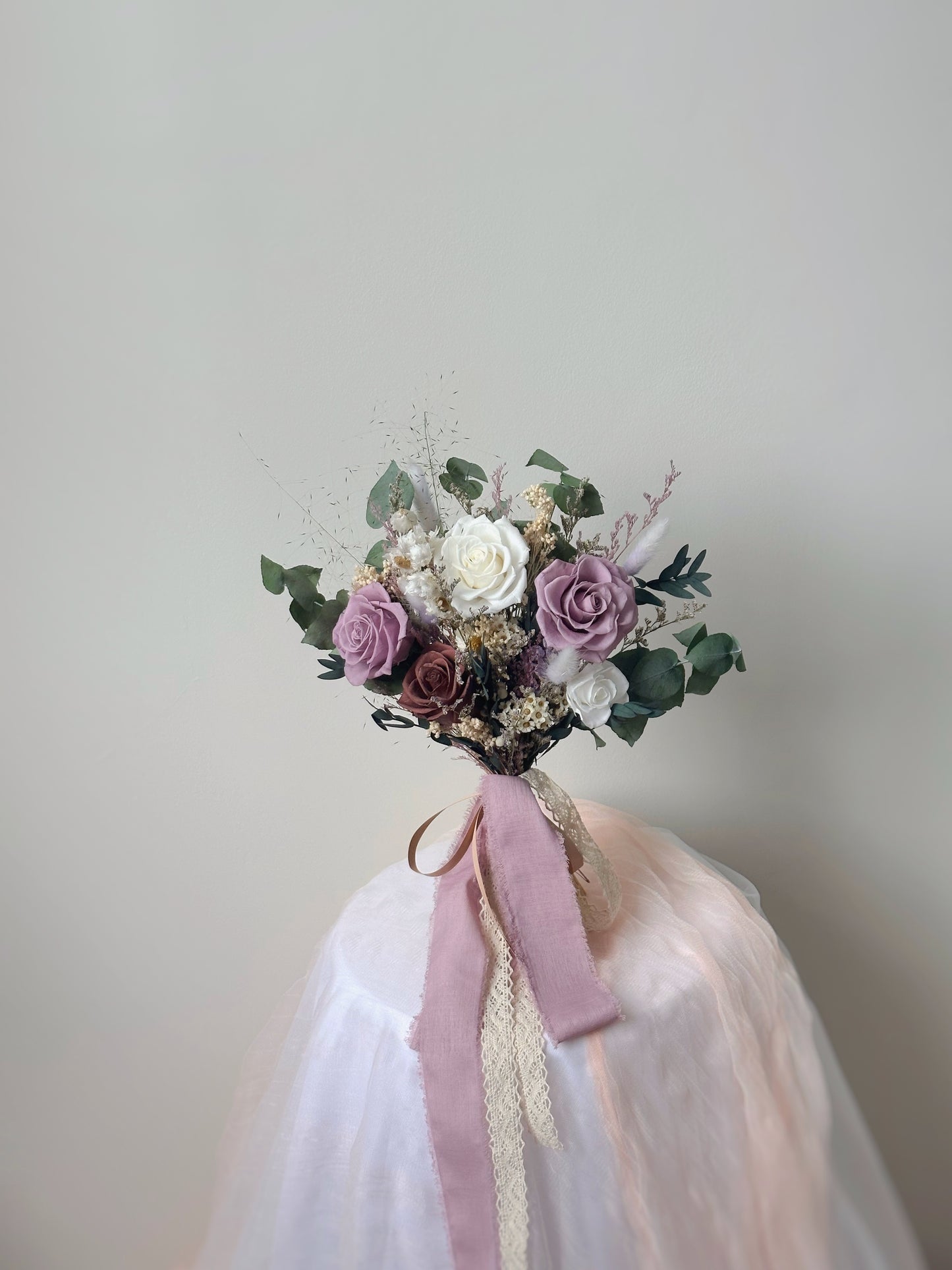 A fan-shaped preserved bouquet in soft lilac, white, and khaki tones, exuding a dreamy, romantic aesthetic.
扇形永生花捧花,采用柔和的紫丁香、白色与卡其色调,散发梦幻浪漫氛围。