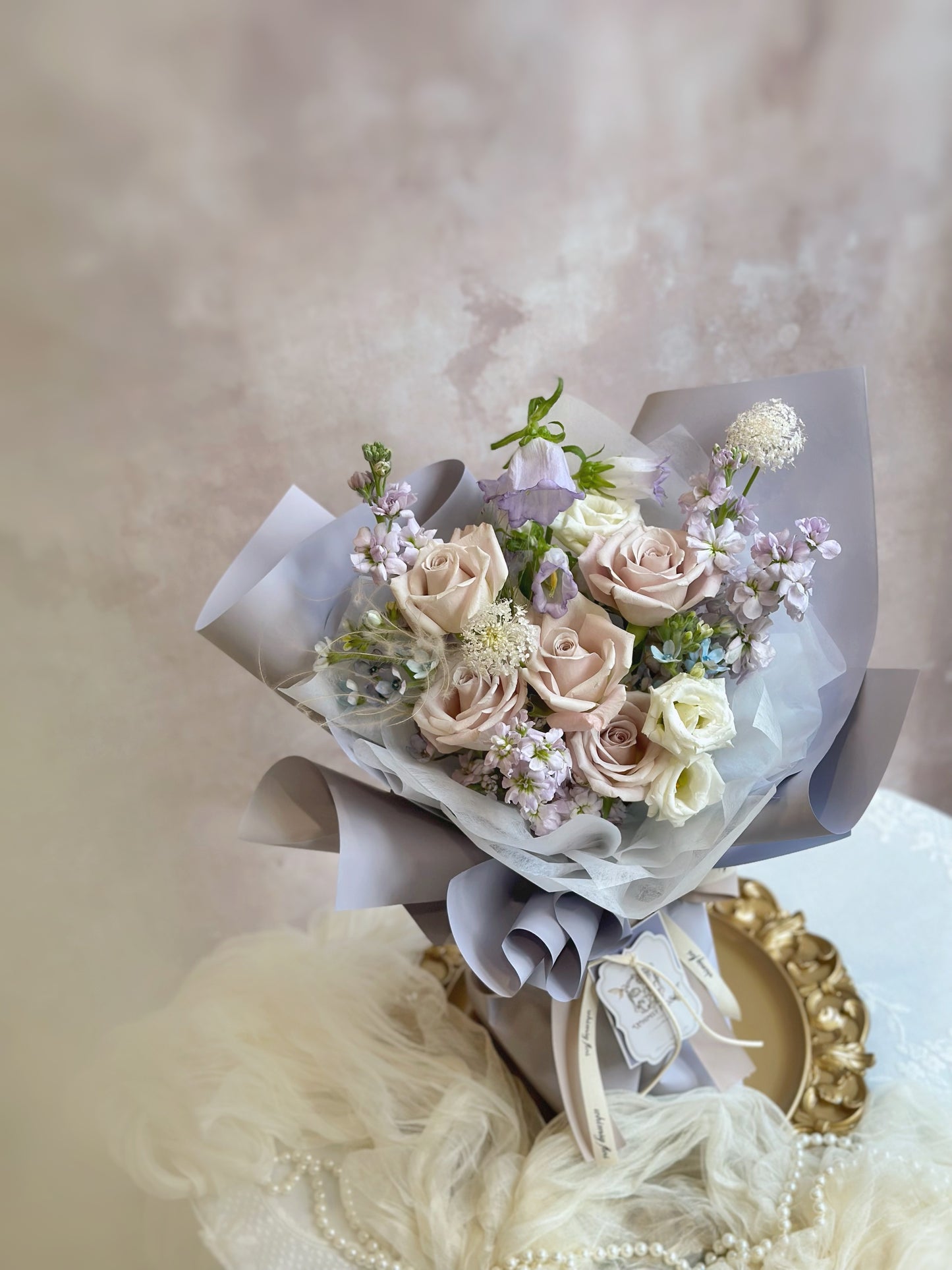 Top-down view of lilac tone fresh flowers bouquet featurings matthiola, roses, tweedia flowers, eustoma and etc.