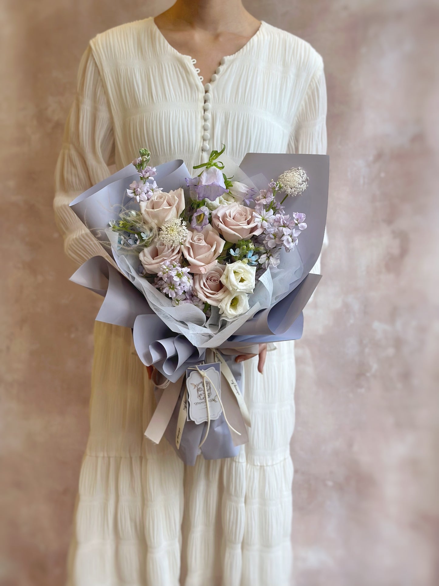 Lilac tone fresh flowers handtied bouquet held in hand, capturing a whimsical, serene moment.
手持淡紫花束,营造梦幻宁静的生活氛围感。
