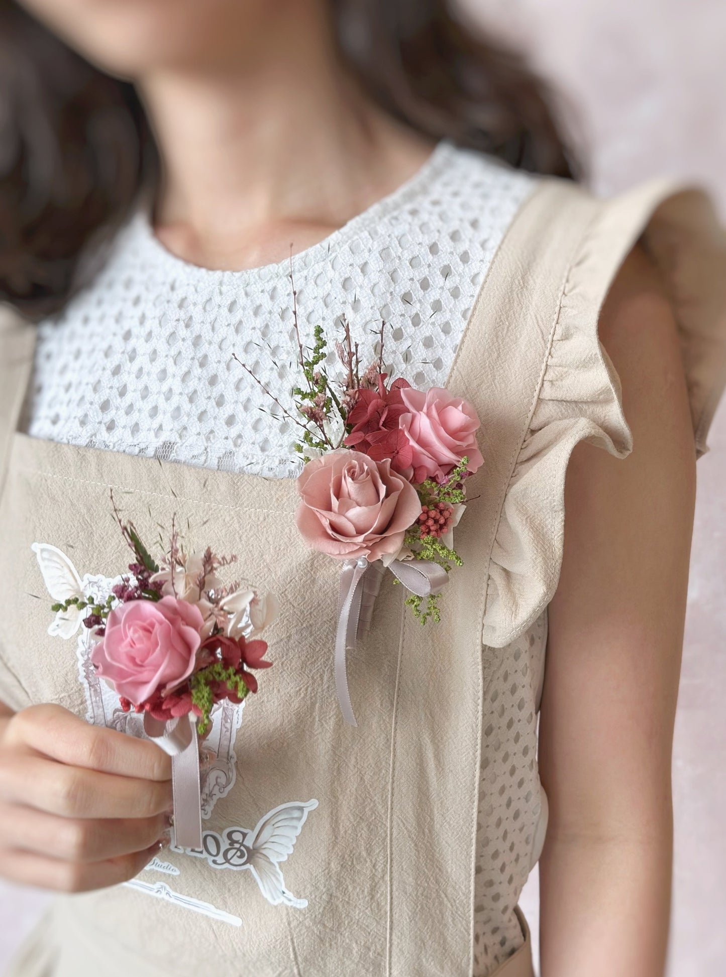 Model wearing a Mei Hwa double preserved rose boutonniere while elegantly holding a single preserved rose boutonniere, showcasing the single and double rose designs for a refined wedding look