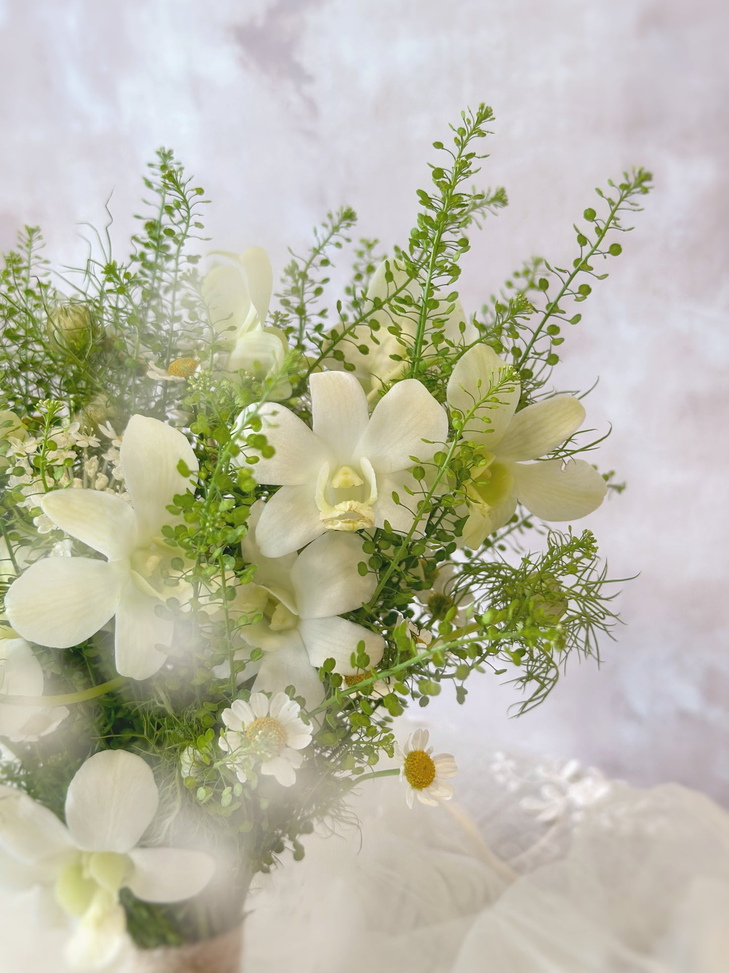 Misty forest fresh flowers bridal bouquet close up view, featuring white dendrobium orchid, chamomile, thlaspi green bell foliage and other fillers