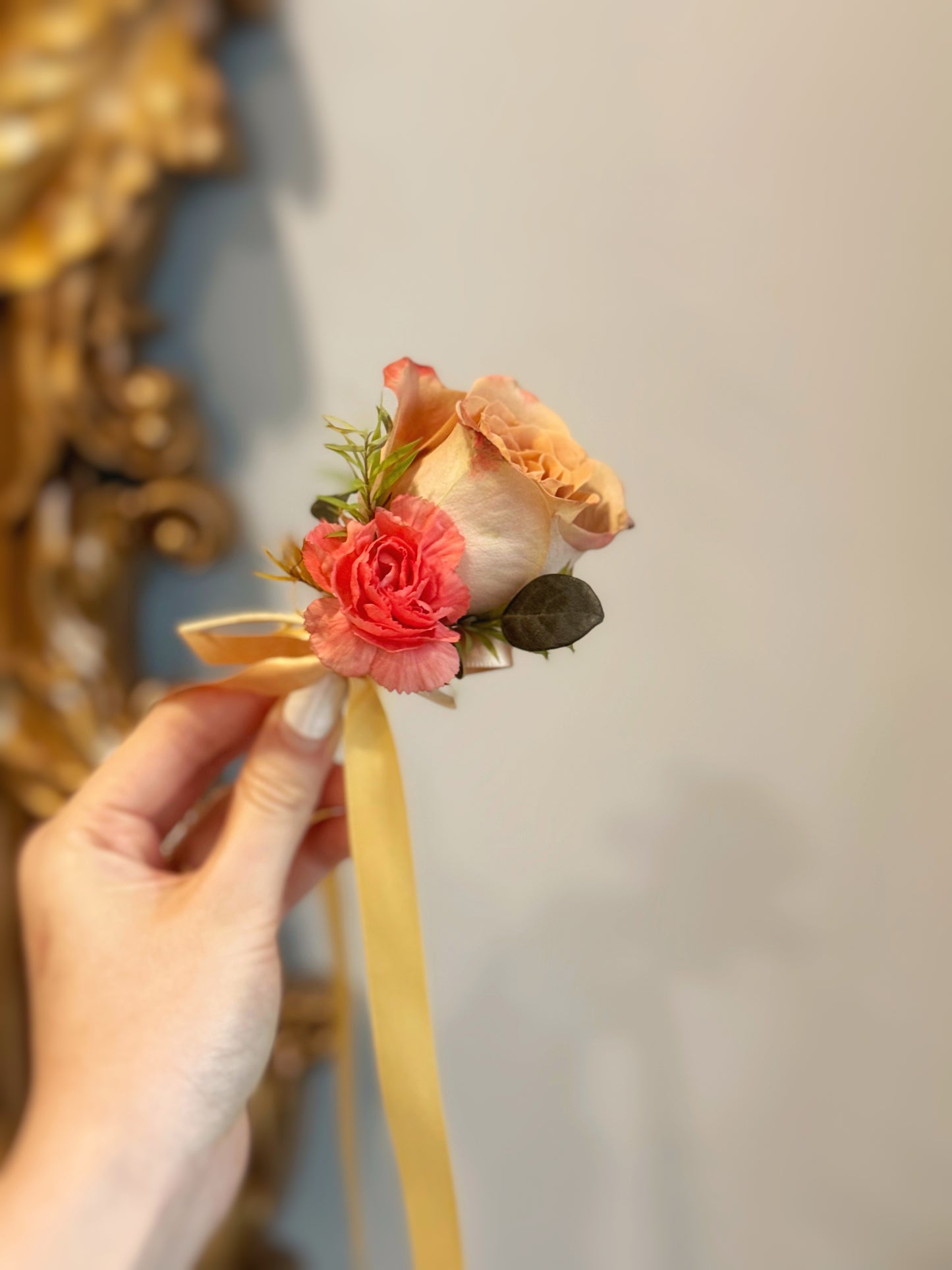 A hand holding the Mocha Sunset corsage, showcasing its delicate floral details and elegant autumn-inspired color palette.