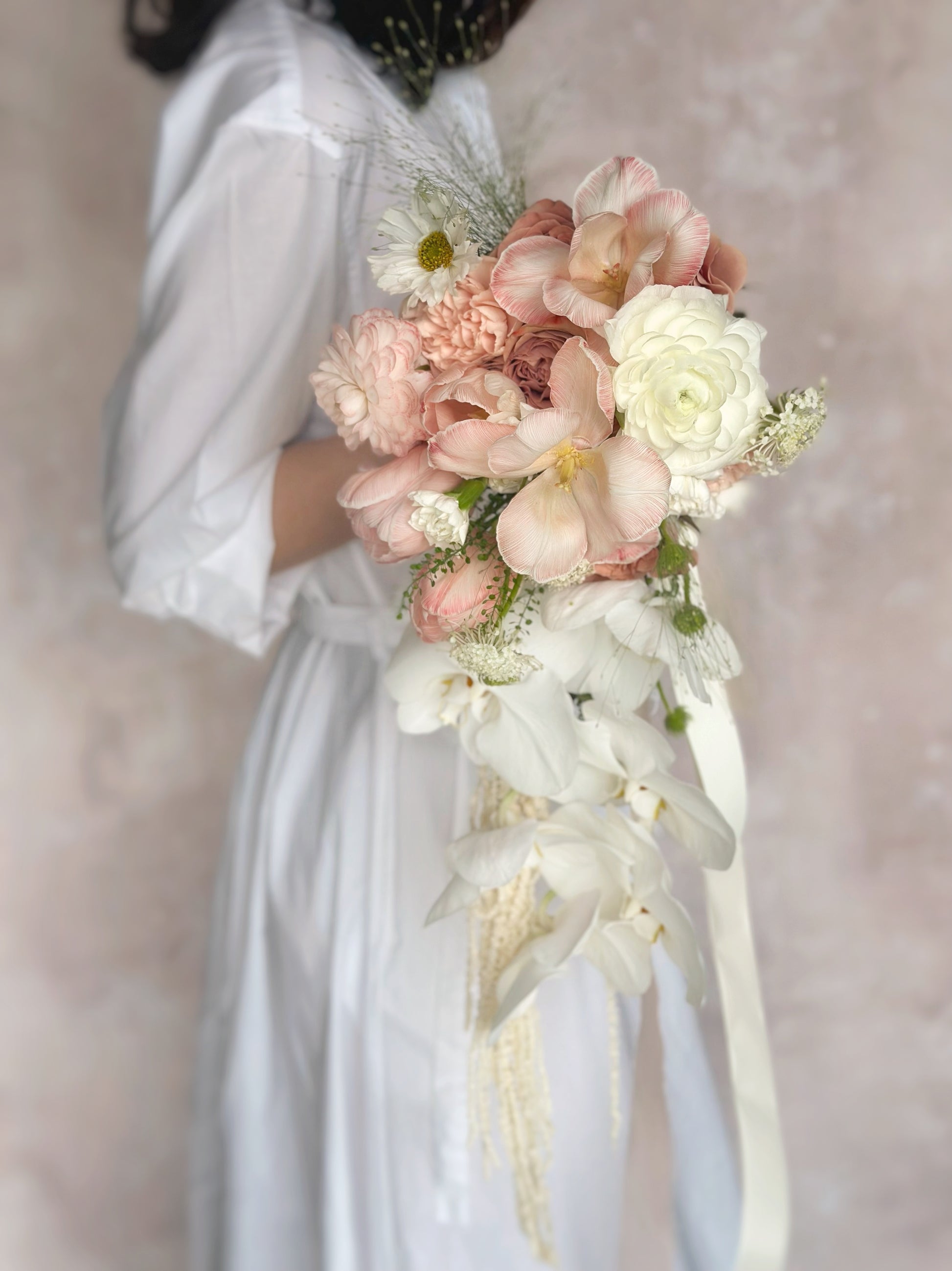 A model holding a cascading peachy pink bouquet, enhancing her soft and feminine bridal look
新娘手持蜜桃粉色蝴蝶兰水滴型捧花,尽显柔美优雅