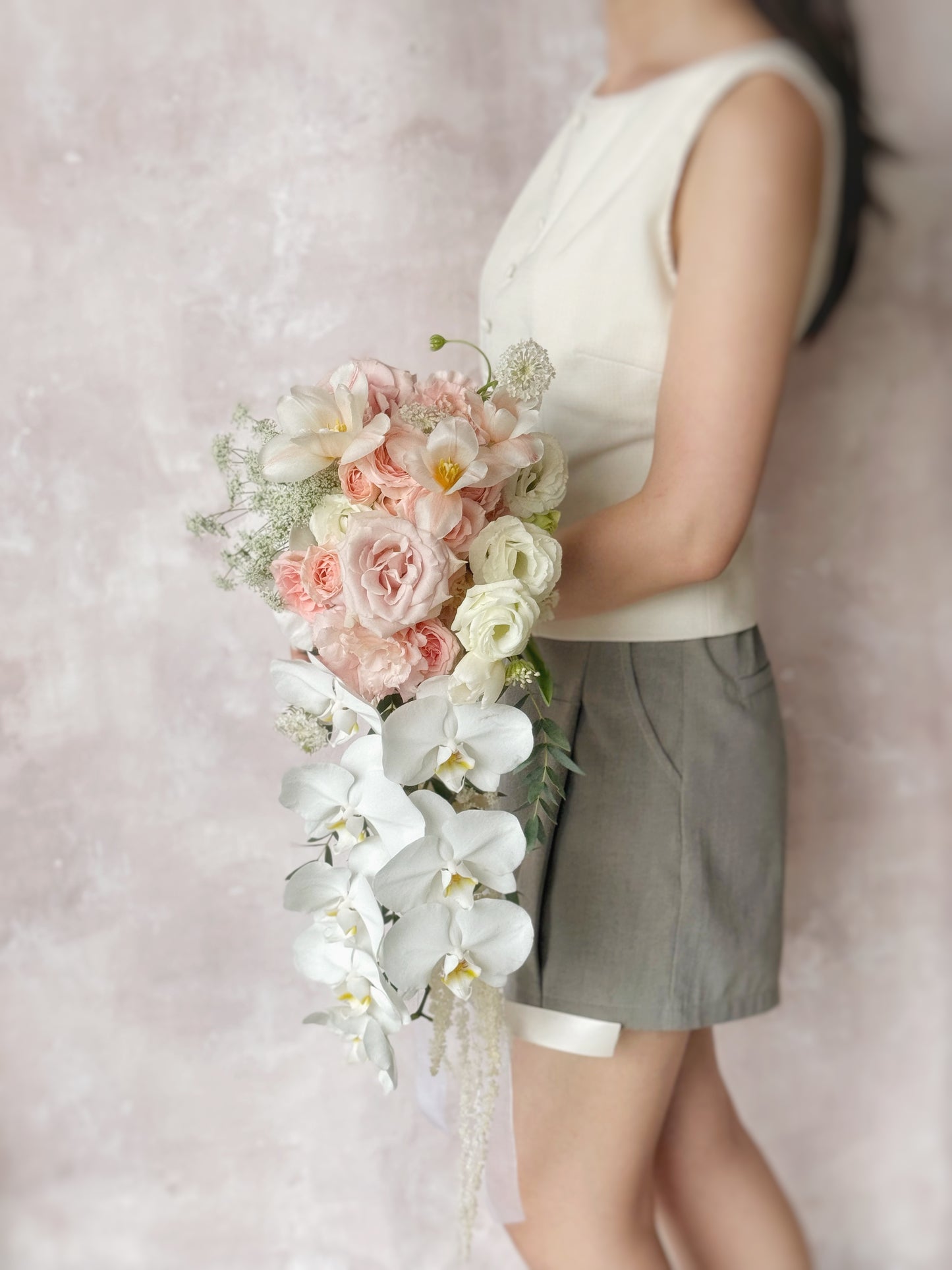 A cascading bouquet in warm peach tones, complementing a romantic bridal ensemble
温暖蜜桃粉色瀑布式捧花,与新娘造型完美融合