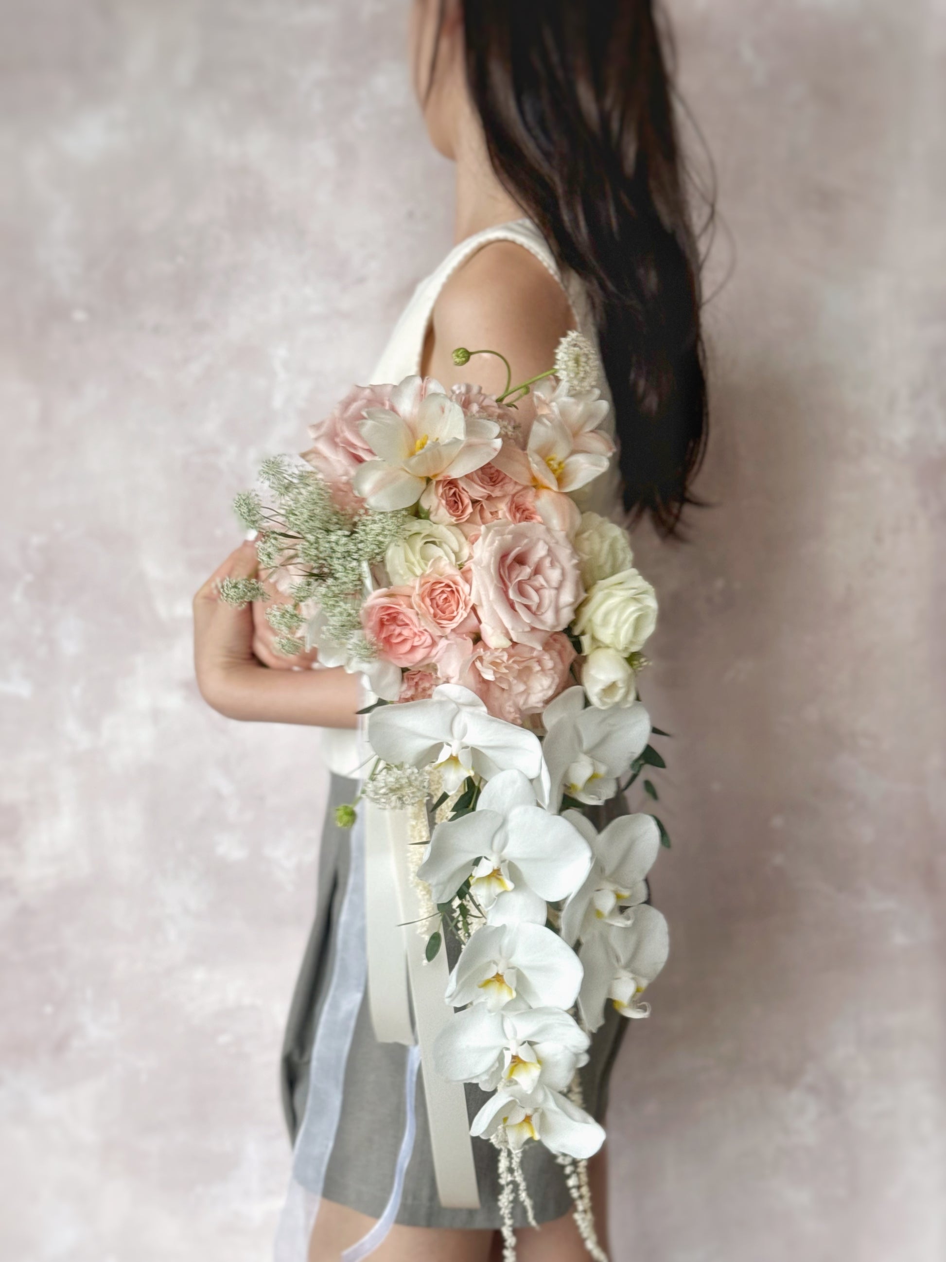 A graceful, cascading bouquet featuring dreamy peach-toned florals for a timeless wedding look
以梦幻蜜桃色花卉打造的优雅瀑布式捧花,尽显经典新娘气质