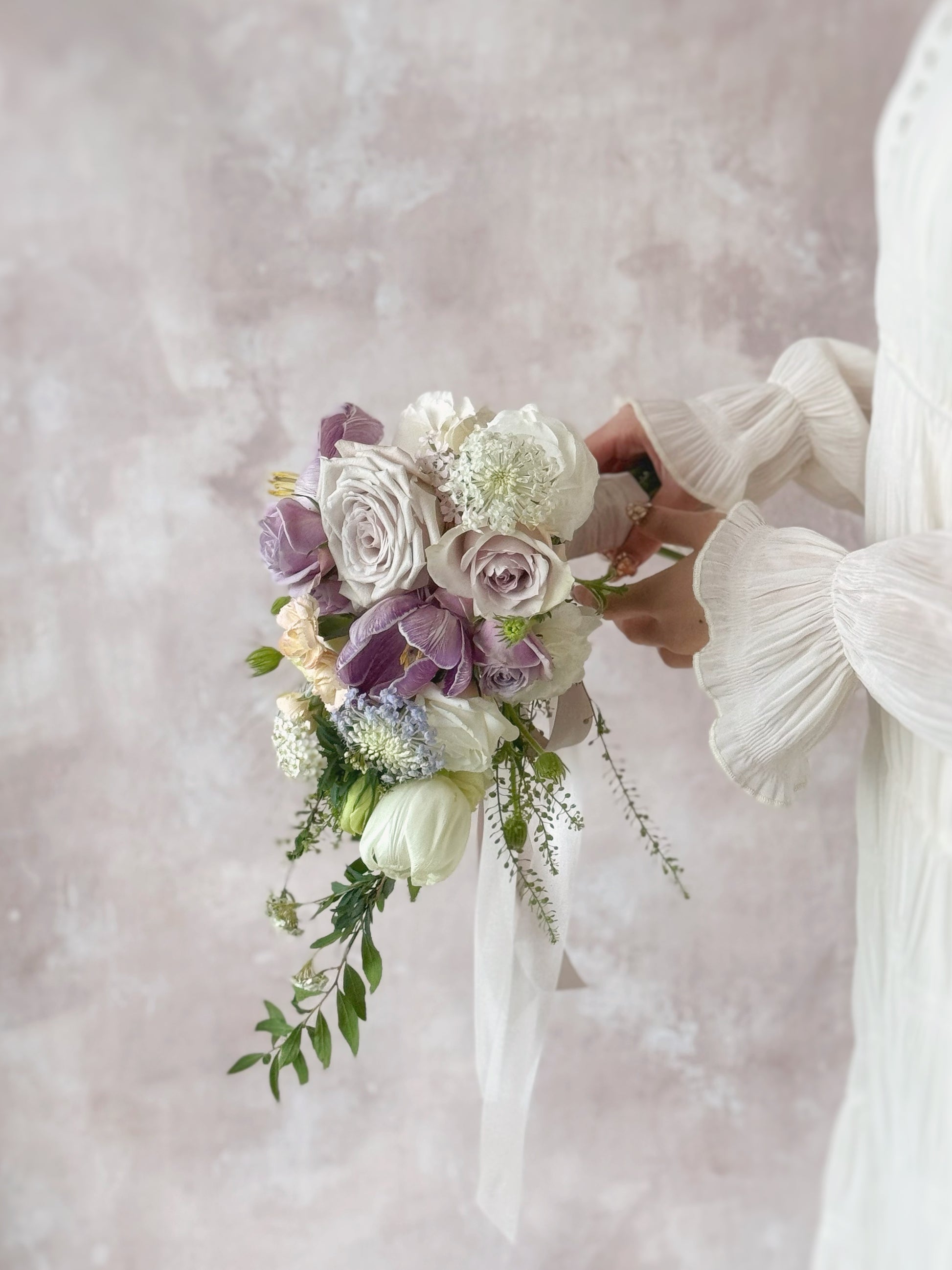 A romantic teardrop bouquet with flowing orchids, held by a bride for a graceful and sophisticated wedding aesthetic
新娘手持 Ocean Eyes 捧花,流畅线条尽显高贵优雅