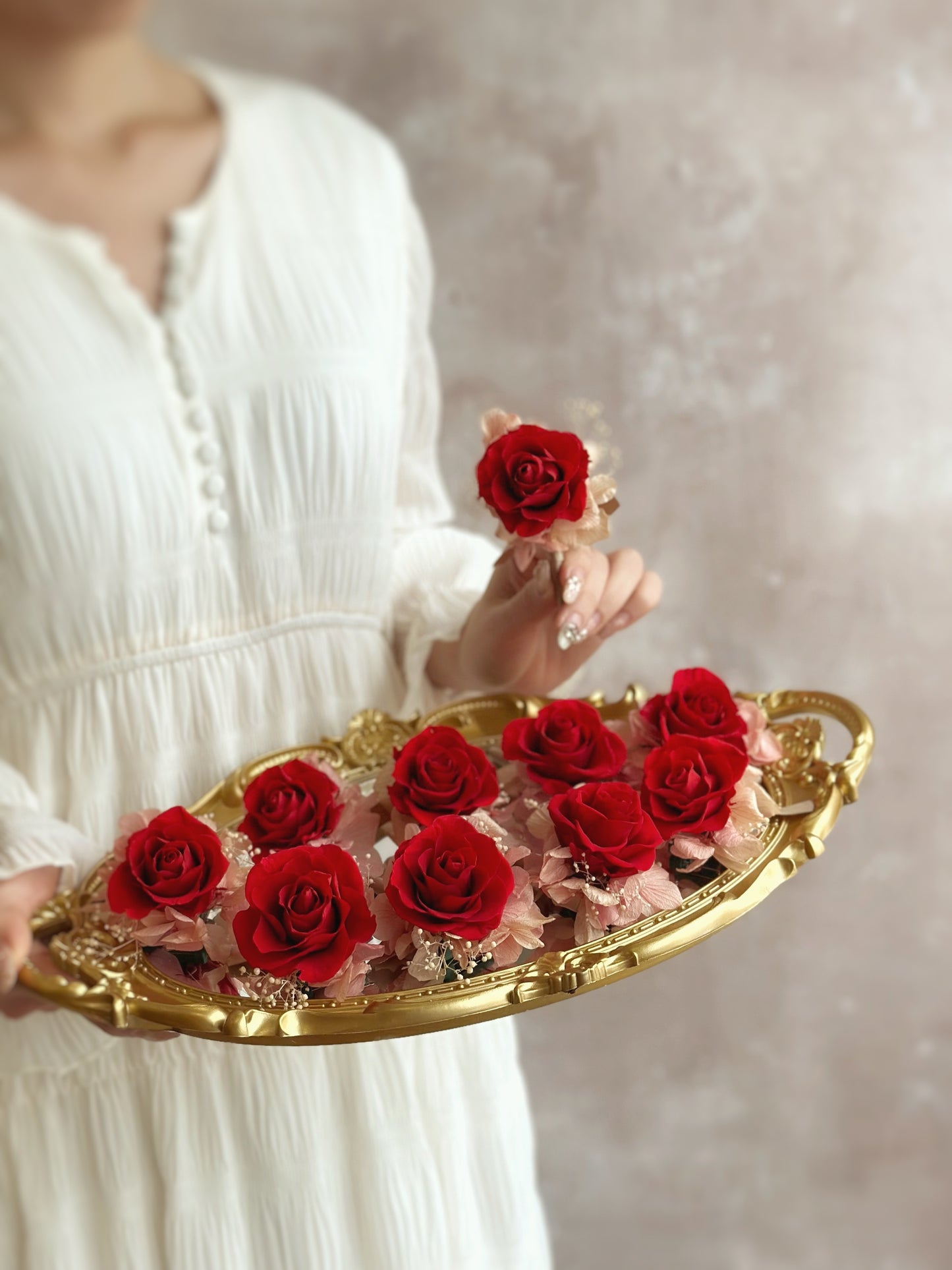 holding a tray of carefully arranged boutonnieres, showcasing multiple red oriental theme Poppy preserved flowers boutonnieres