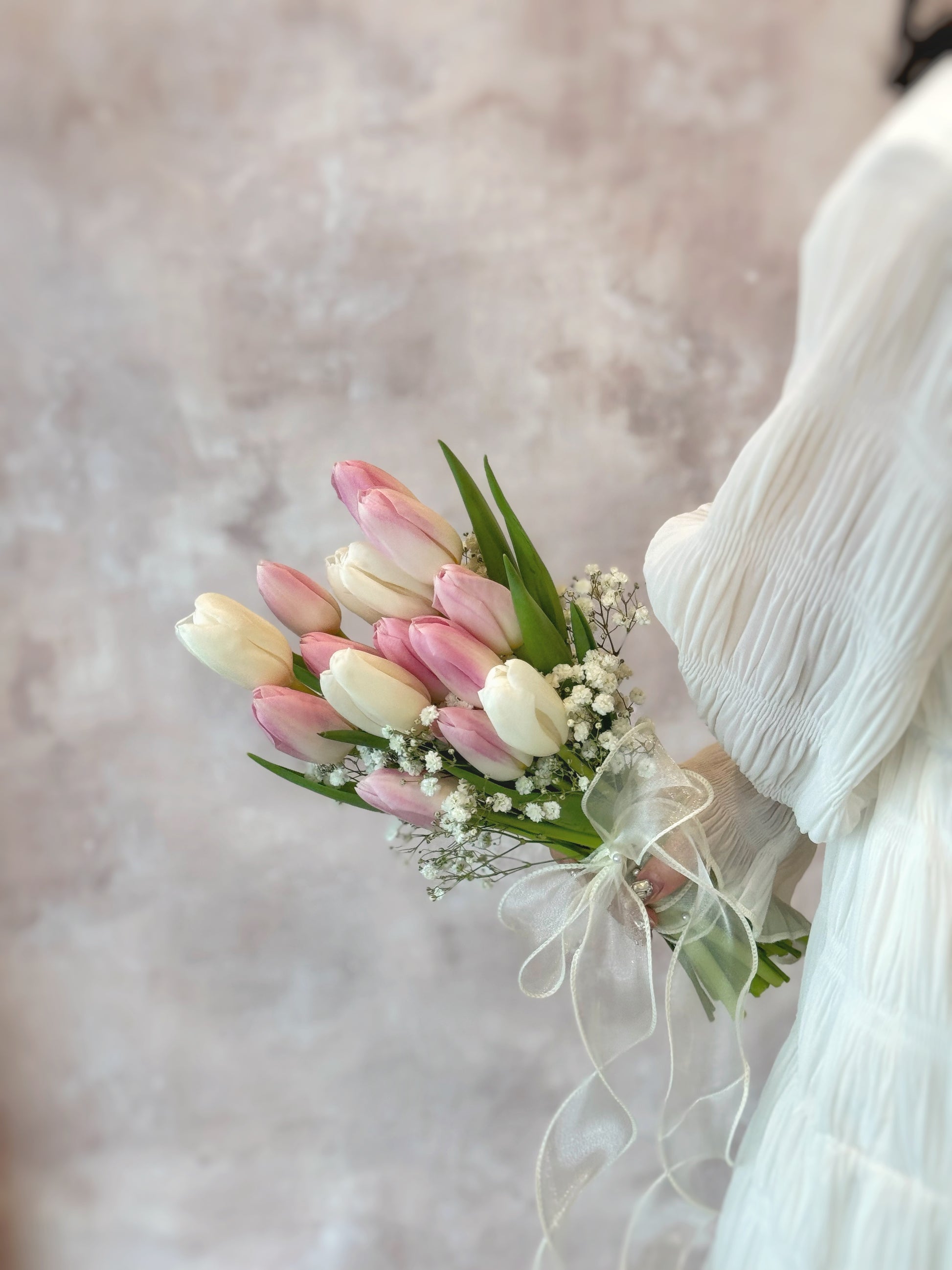 The soft hues of tulips and baby’s breath complement the bride’s elegant and feminine look
粉白郁金香与满天星的柔和色调,完美衬托新娘的优雅气质