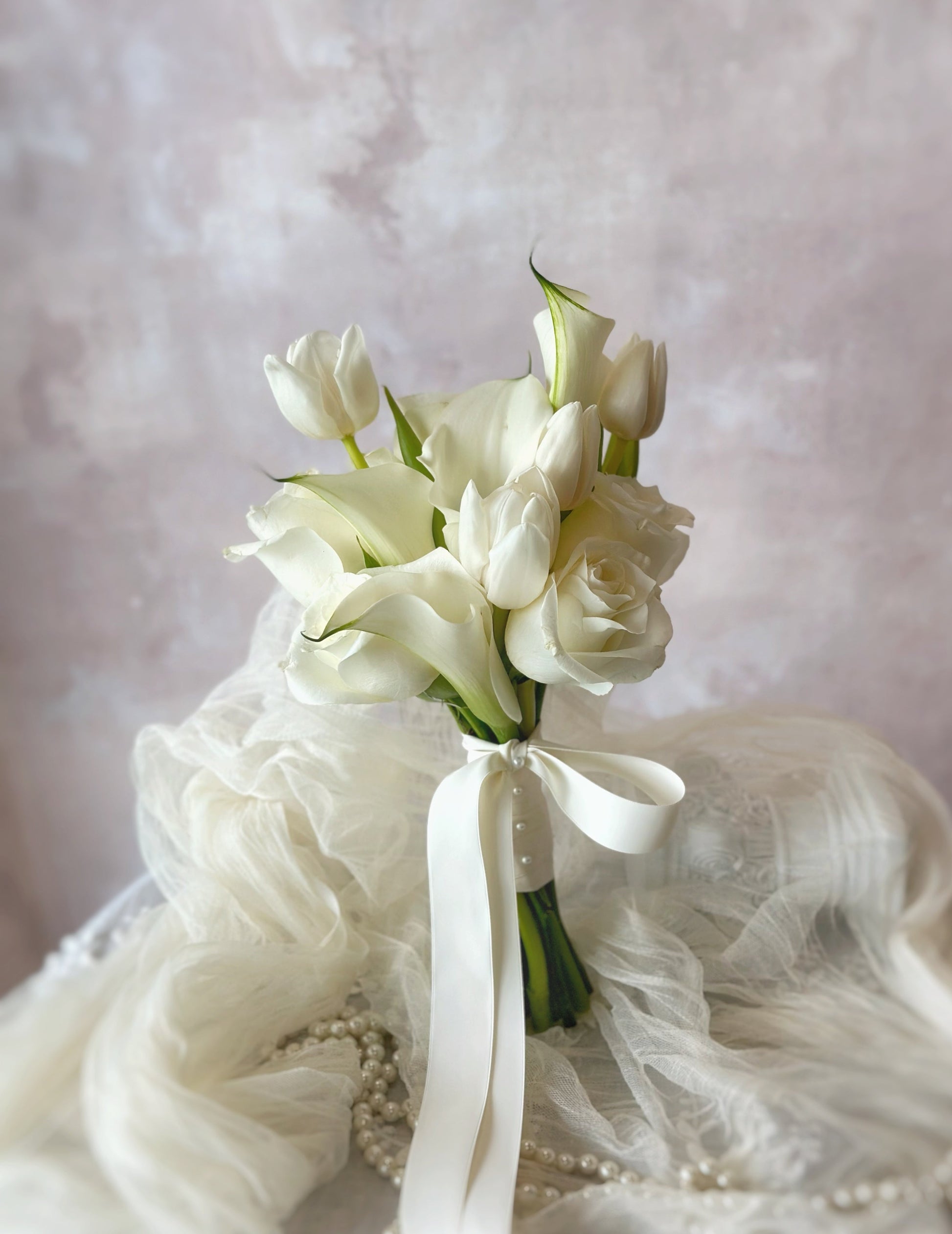 A premium white bridal bouquet featuring calla lilies, tulips, and roses for a timeless elegant look
经典优雅的白色新娘捧花,融合马蹄莲、郁金香和玫瑰,展现永恒之美