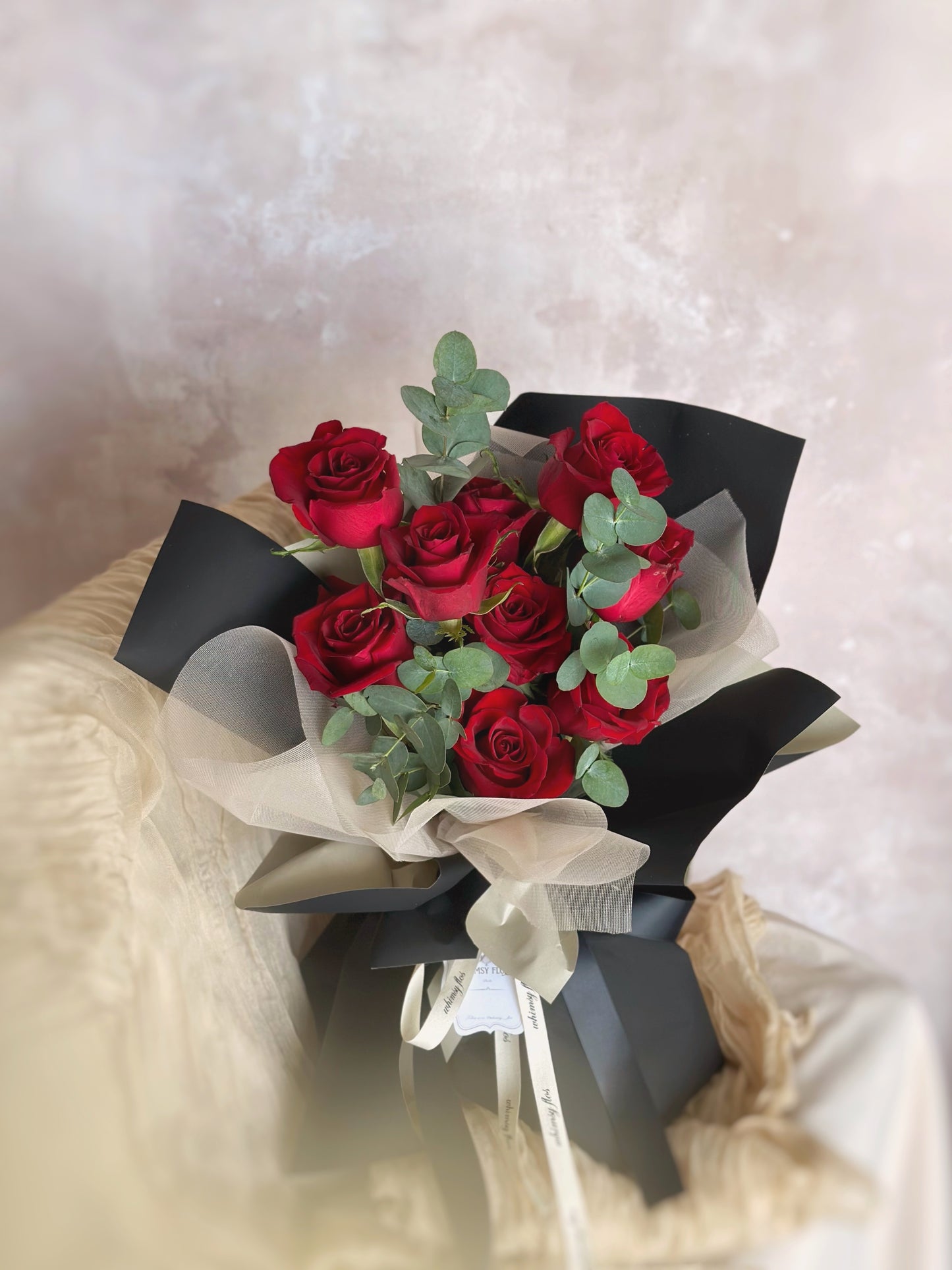 Bouquet displayed on a chair, showing off the rich colors and textural contrast of the blooms and stylish wrap under natural light.
花束平放于椅子上,自然光下展现花朵与包装的色彩对比与质感,静谧中透露时尚氛围。
