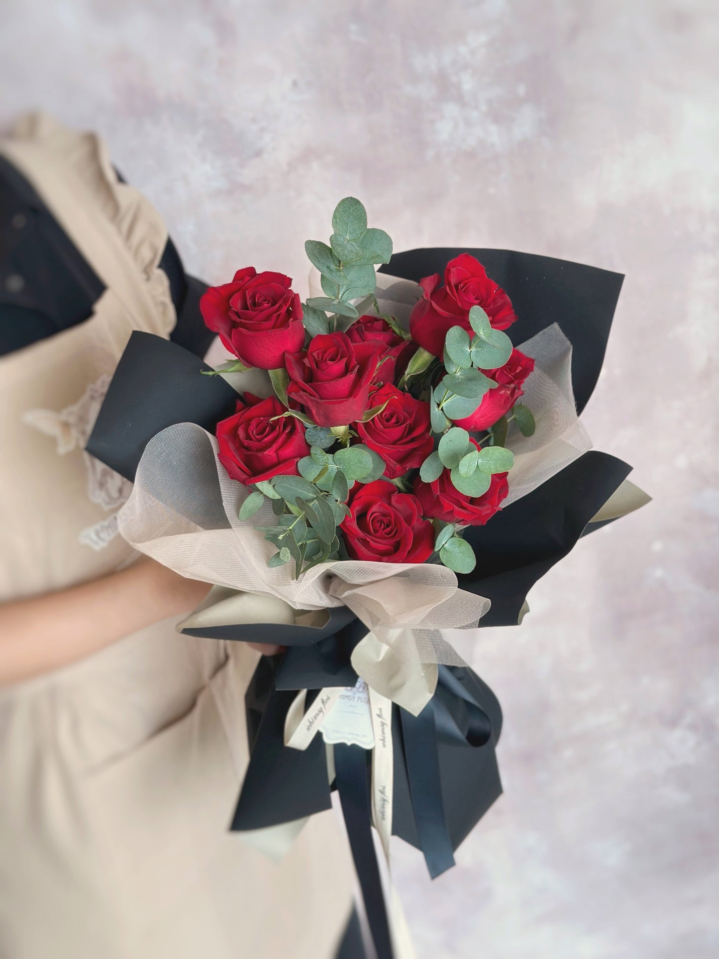 Model holding the bouquet in hand, highlighting the bold red blooms and the striking black and khaki wrap — a modern romantic gesture.
模特手持花束,鲜红玫瑰与黑卡其包装形成对比,现代感十足的浪漫表达