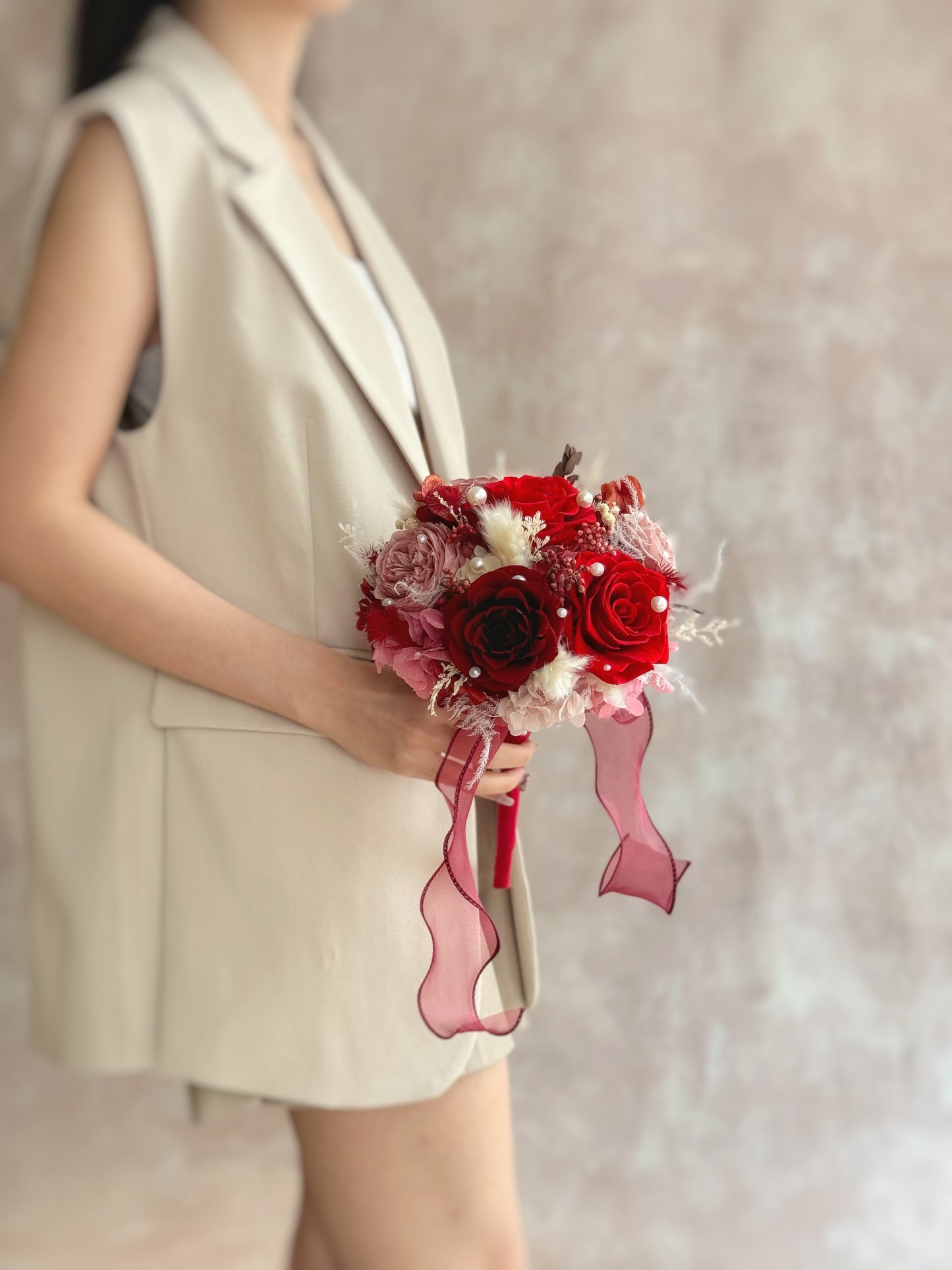 Side angle showcasing the bouquet’s domed shape with layers of preserved blooms and subtle pearl details nestled between the flowers.
侧面视角展现花束饱满圆形轮廓,层层永生花中点缀精致珍珠,散发复古女性魅力。