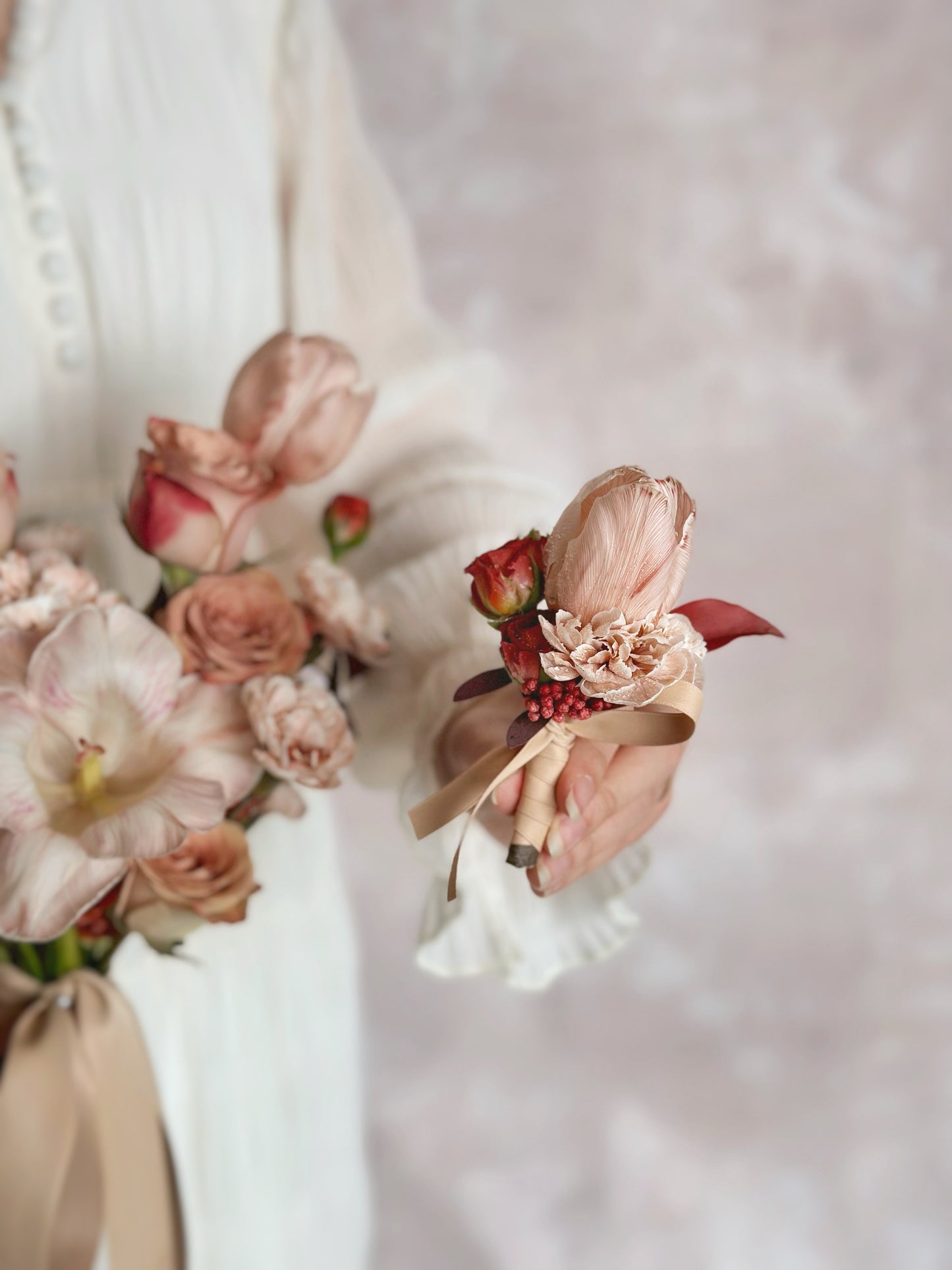 a model holding rosy bronze fresh flowers bridal bouquet and tulip groom's boutonniere