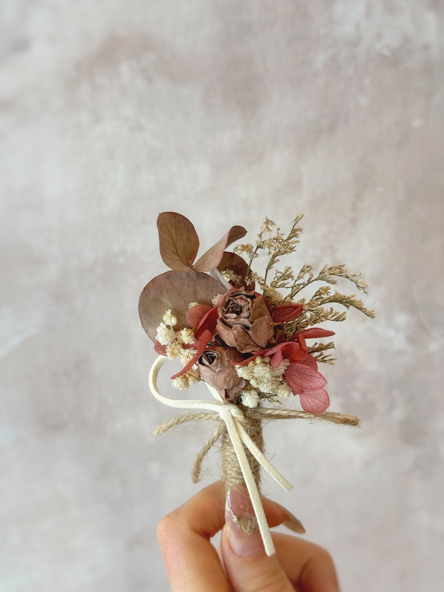 Rustique Rose tinted preserved and dried flowers boutonniere holding by model